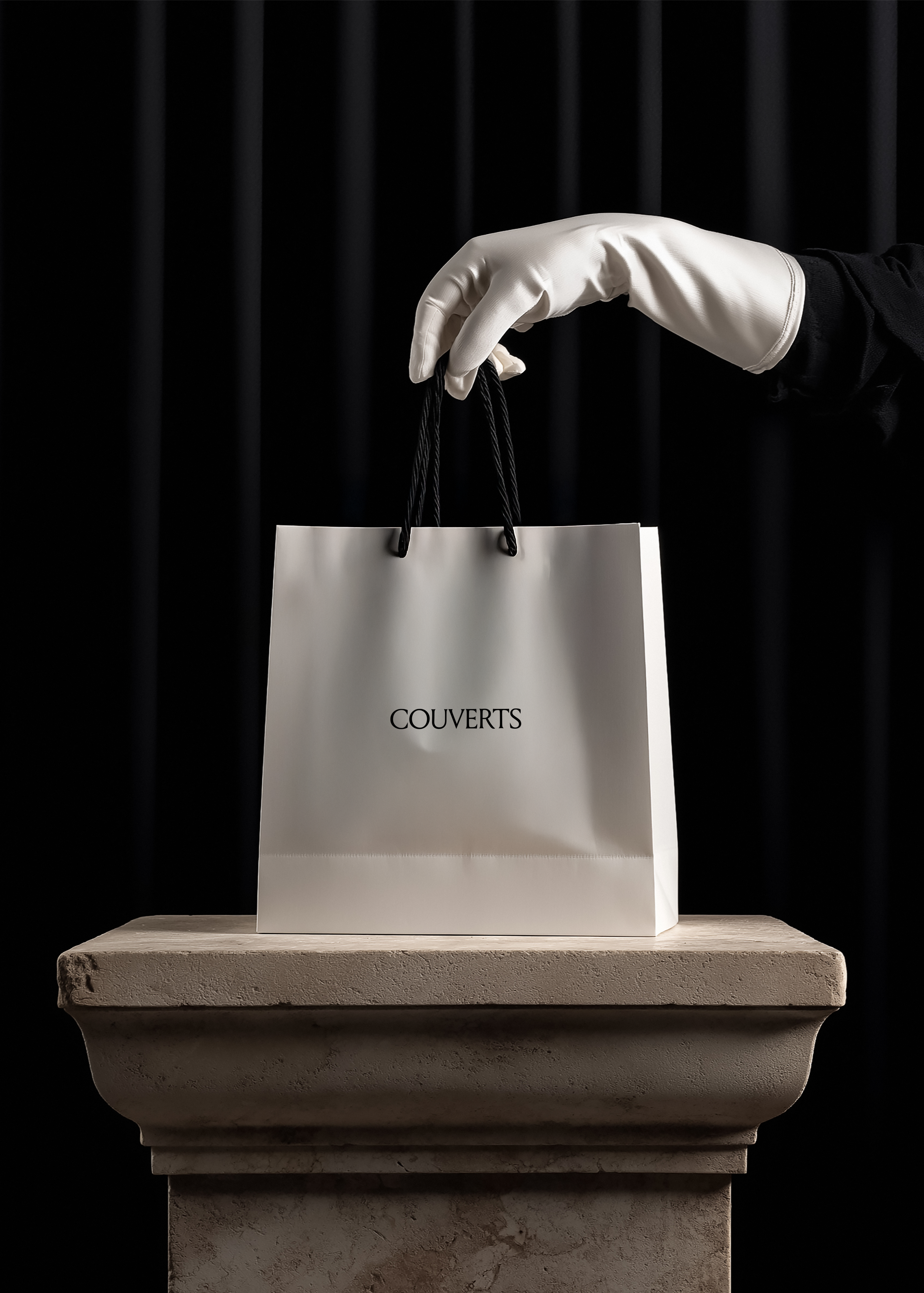 White paper shopping bag with black cord handles lifted by white gloved hand, classical stone plinth, black curtain background, luxury editorial