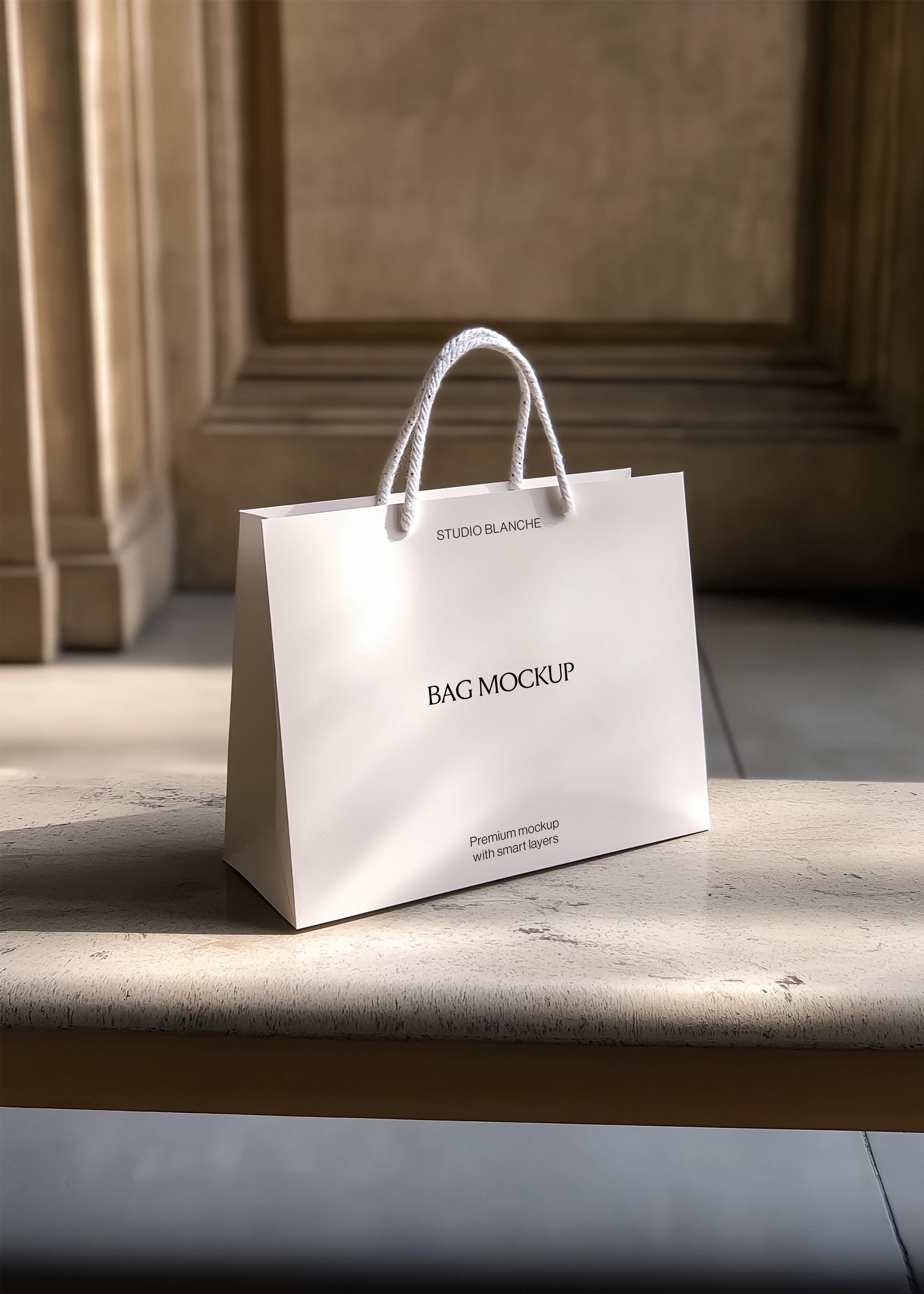 White paper shopping bag mockup with rope handles on a stone ledge, warm light and classical panelling behind