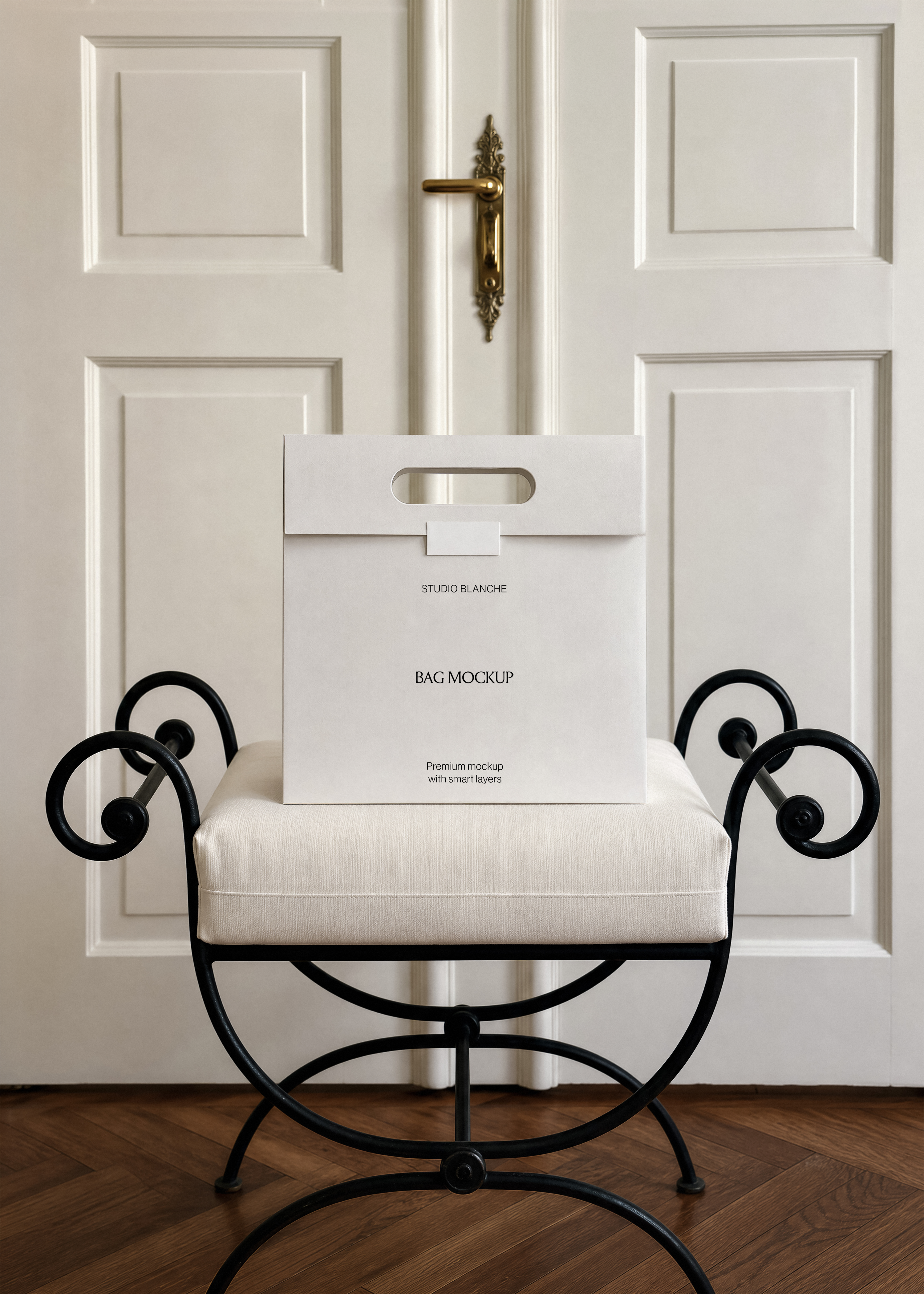 Blank shopping bag mockup on cream cushioned bench, herringbone wood floor and brass door handle in hotel hallway