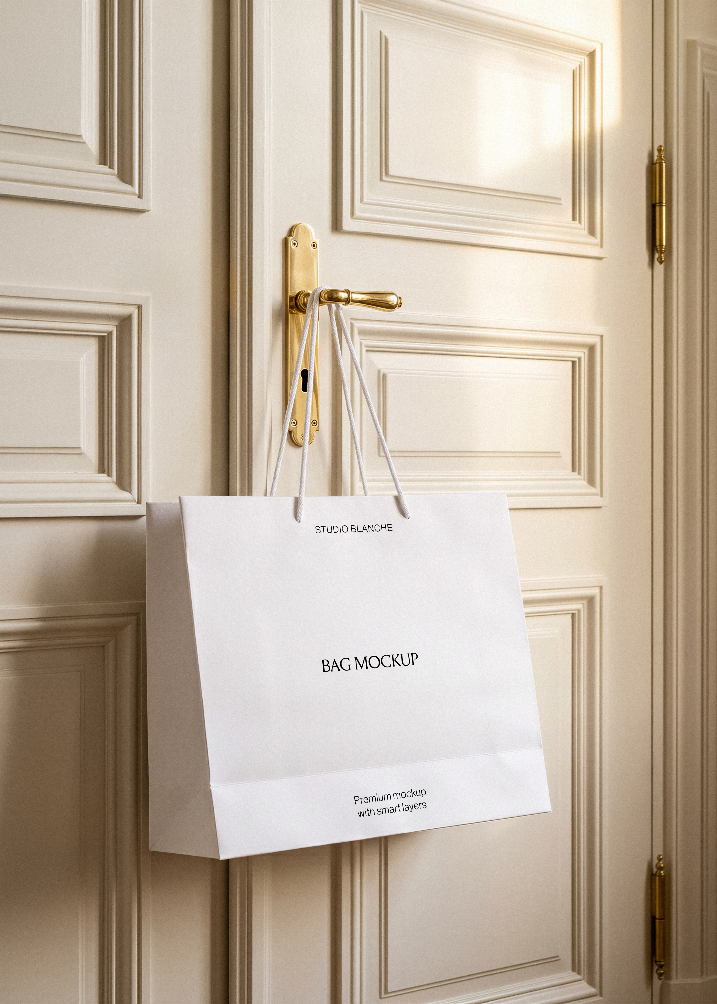 Shopping bag mockup with white rope handles looped over a polished brass lever handle and keyhole plate, warm light