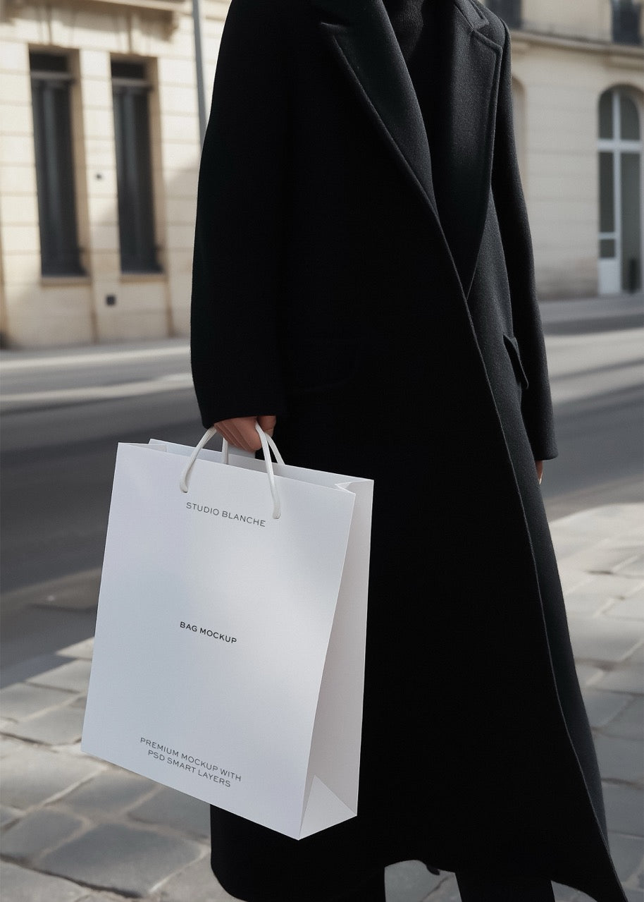 Person holding a white shopping bag with 'Blanche' branding on a street.