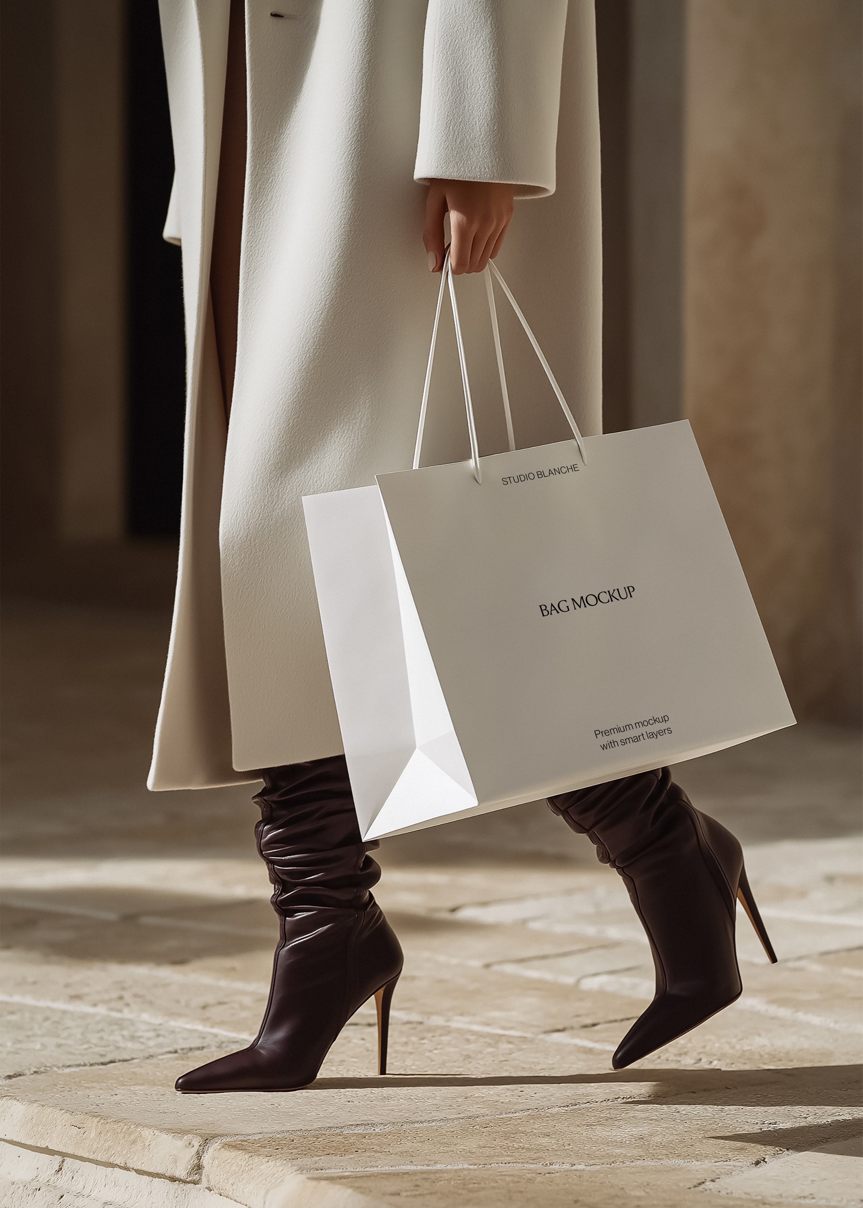 Cream paper shopping bag mockup carried mid-stride by a woman in a cream coat and oxblood boots in warm light