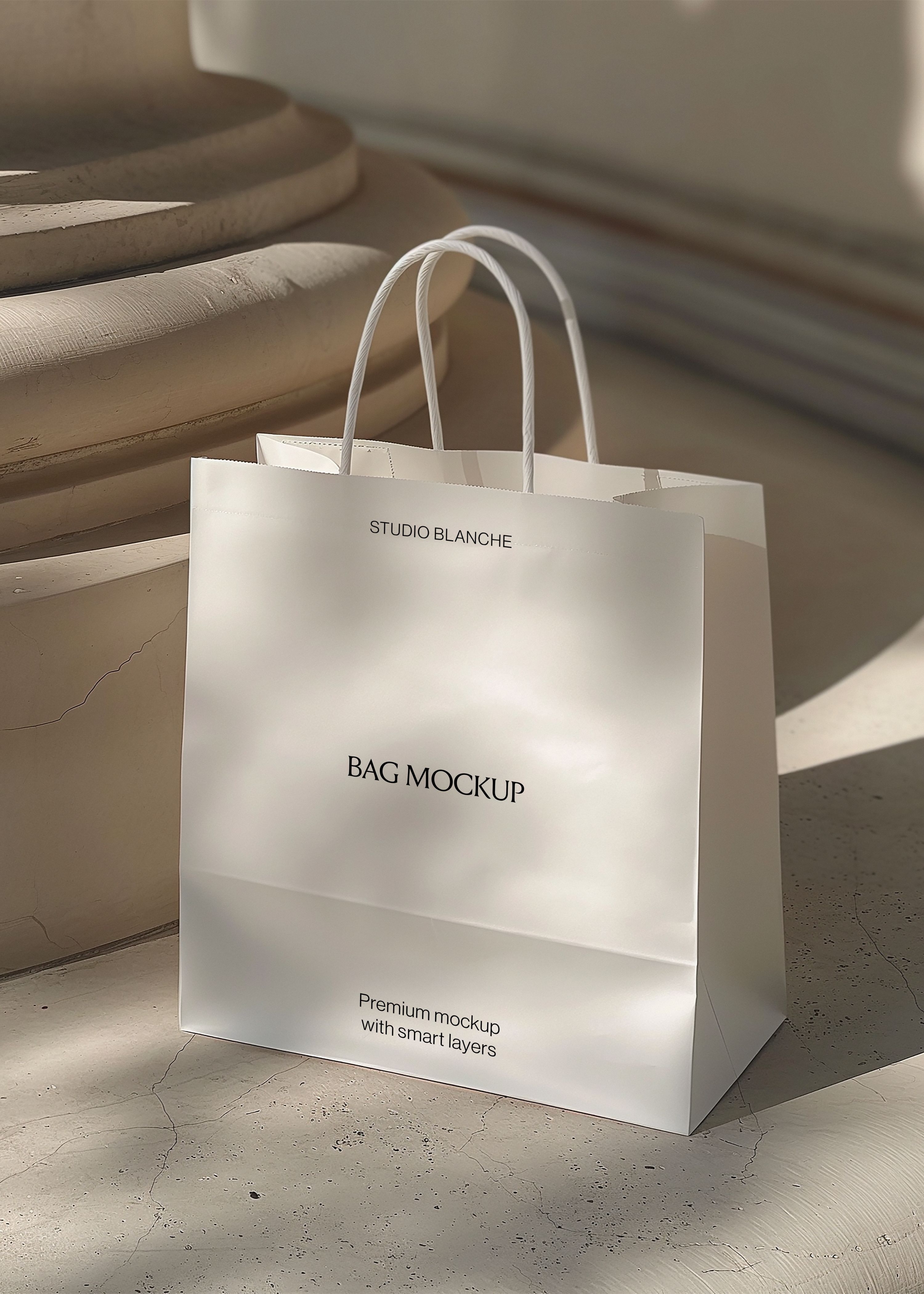 White paper shopping bag mockup with rope handles on a pale stone floor beside a classical column in warm light