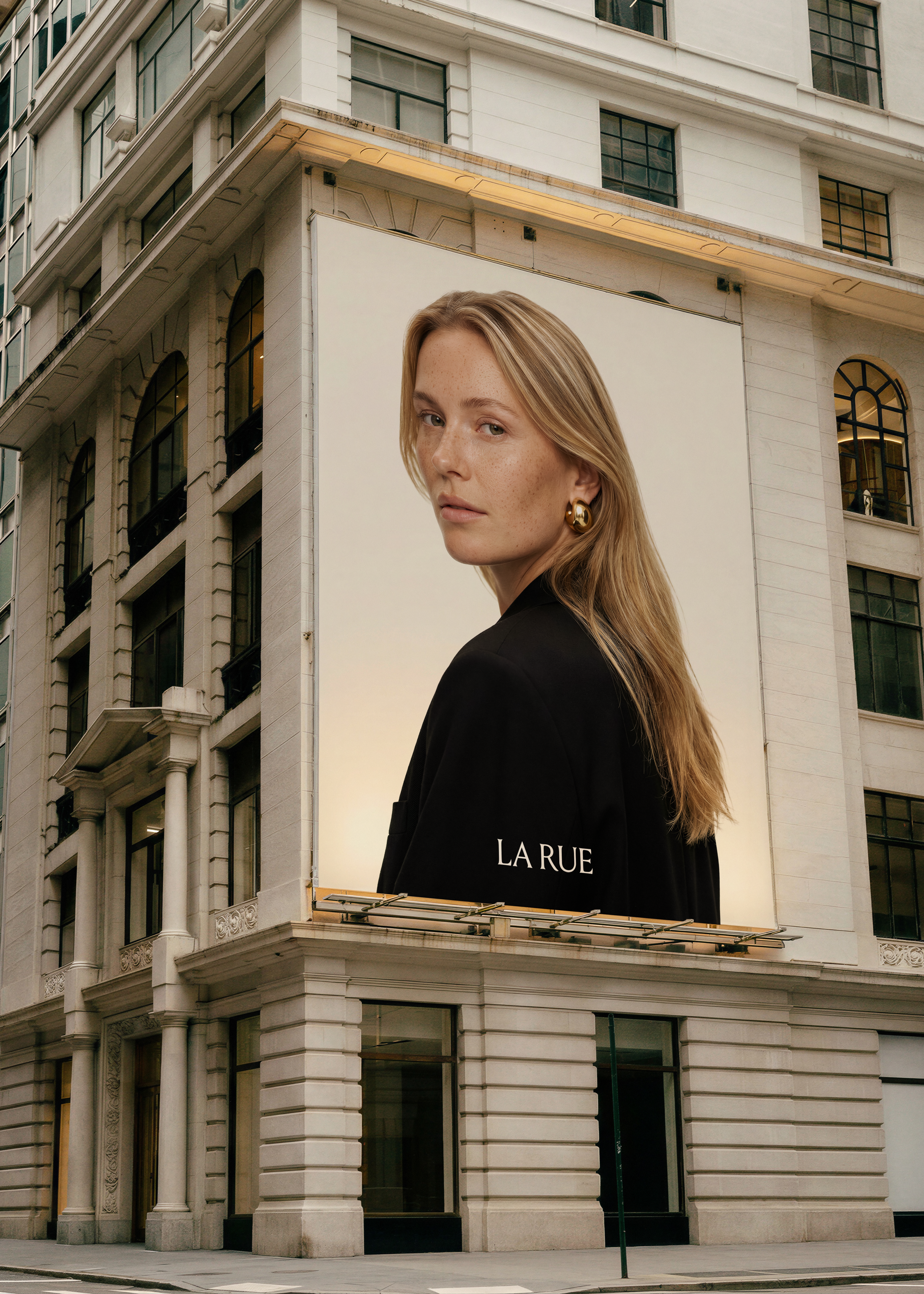 Billboard mockup on a corner building showing a blonde model in black against a cream backdrop with LA RUE branding