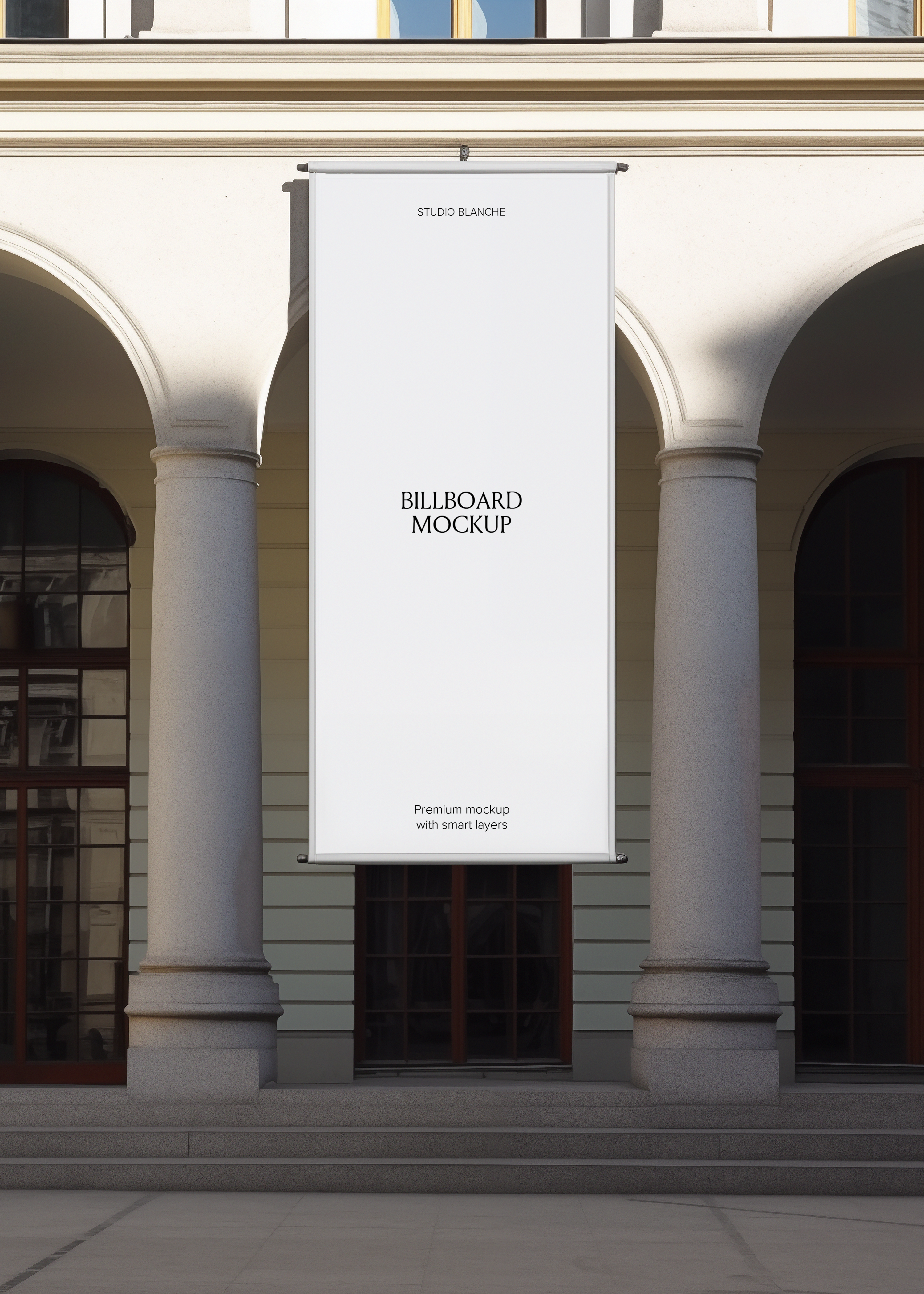 Blank hanging billboard mockup on a colonnaded European building, empty white banner with Studio Blanche label