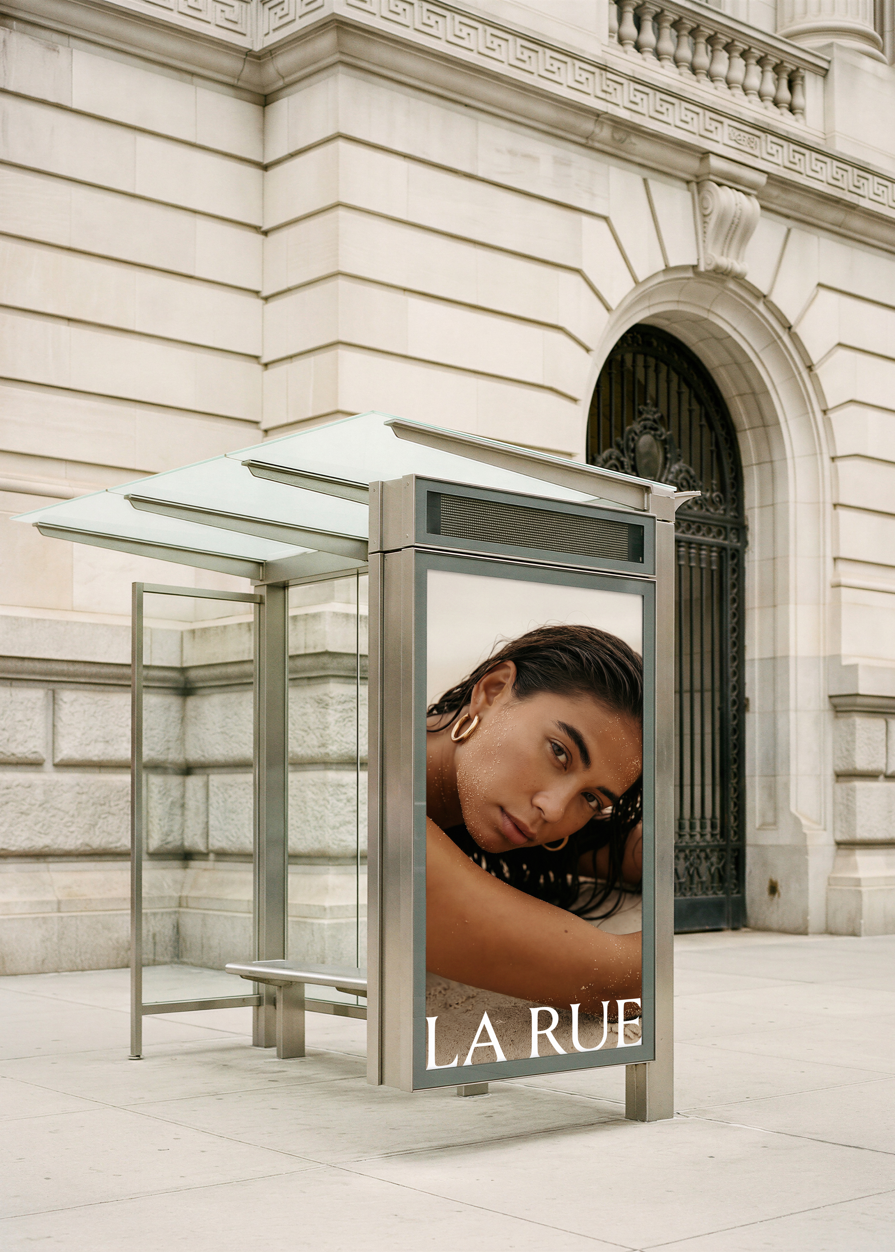Bus shelter billboard mockup with luxury beauty campaign against New York stone facade, from Studio Blanche