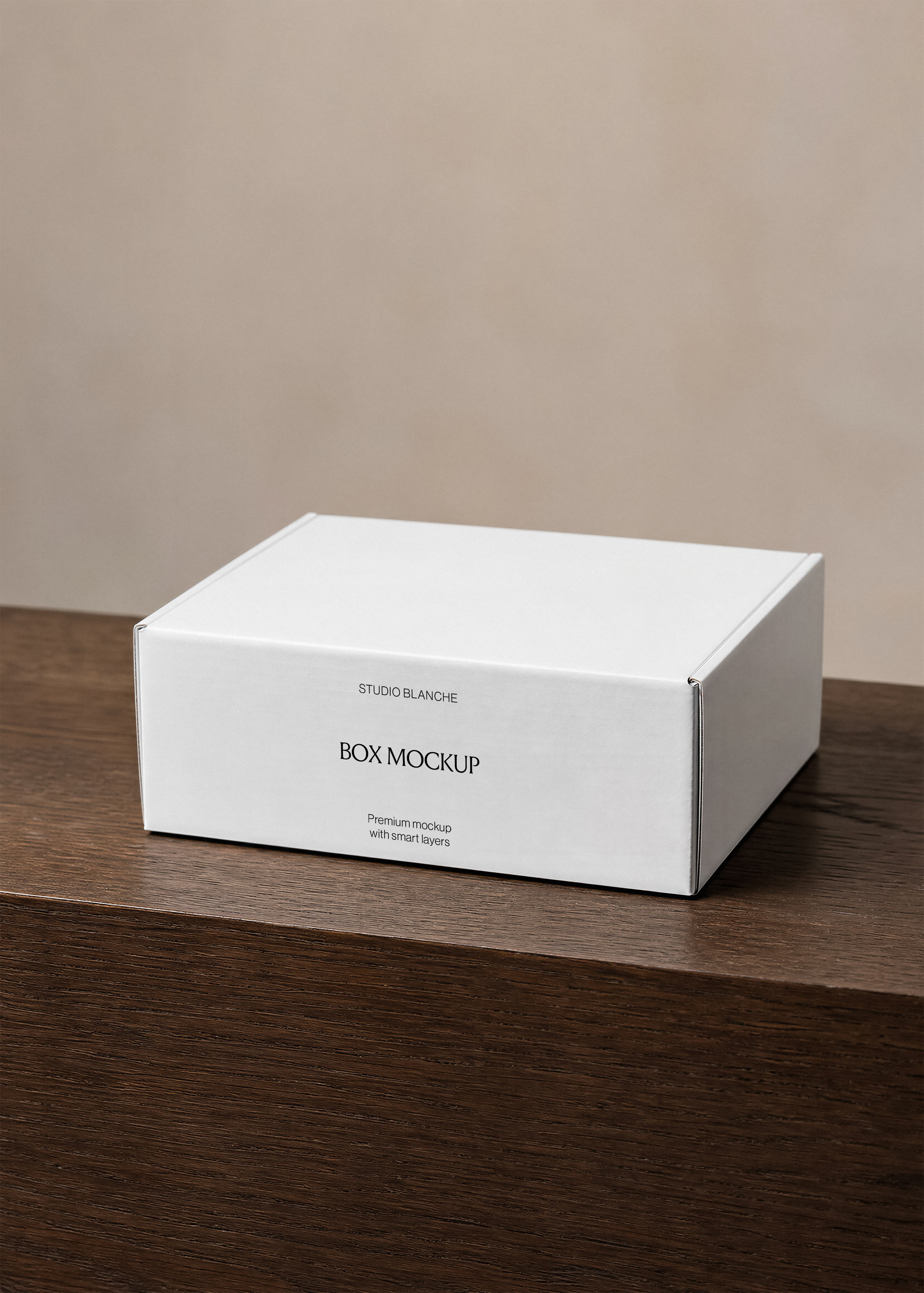 White packaging box mockup with minimal black wordmark label, angled on a dark wood surface, warm neutral background