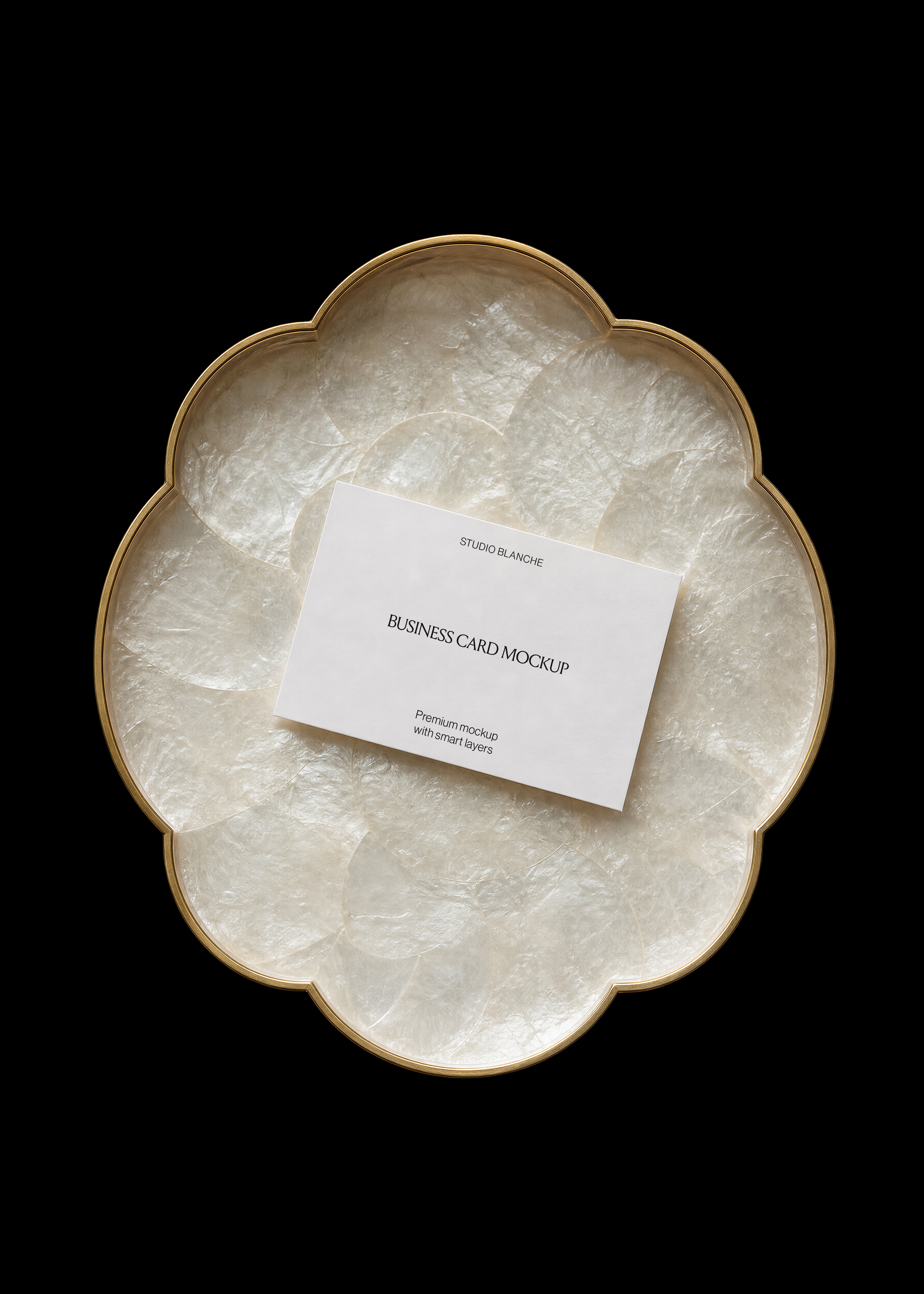 White business card mockup on gold-edged capiz shell tray, centred text layout, dark editorial styling on black ground
