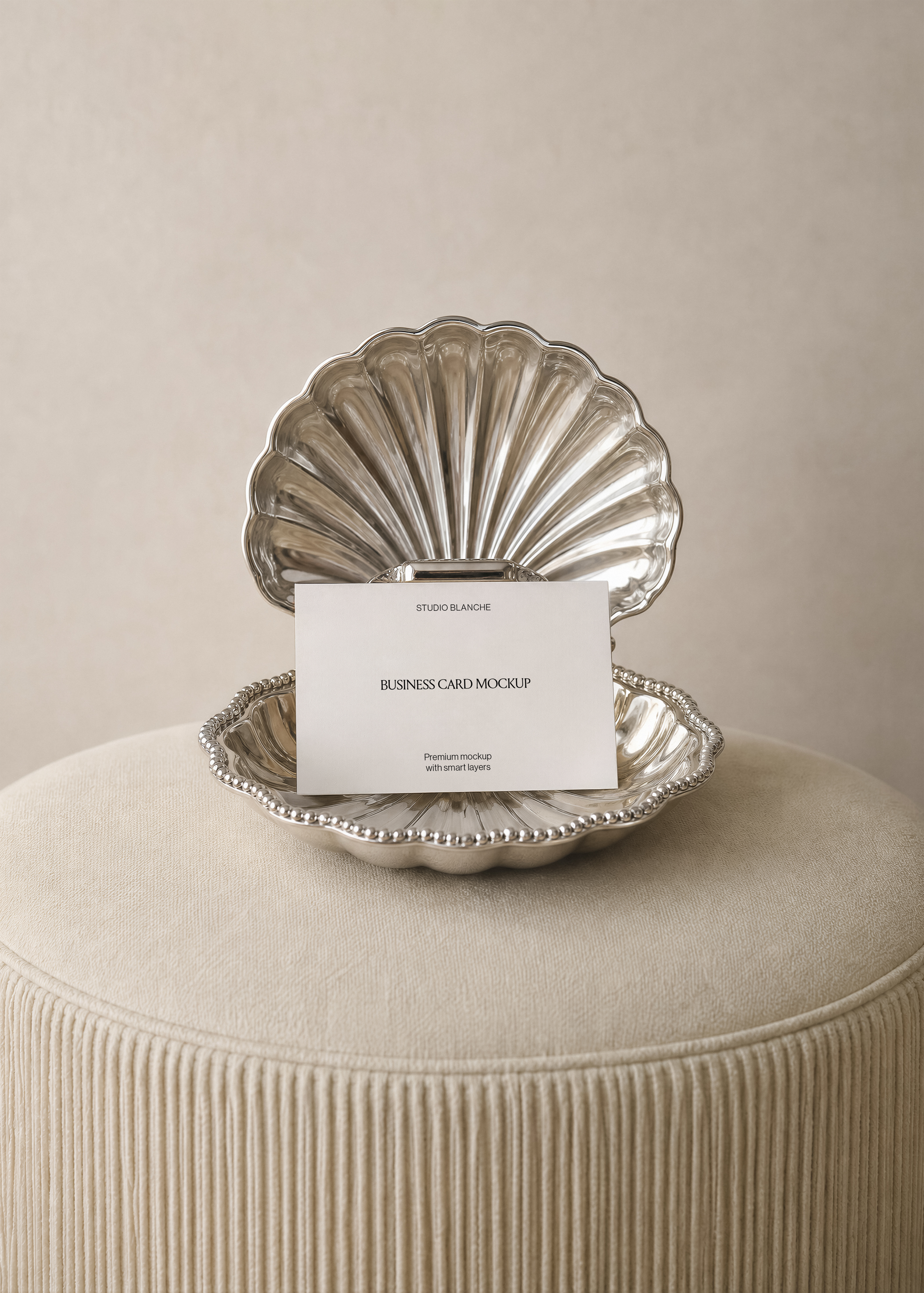 Landscape business card mockup resting in a polished silver shell dish with beaded rim, soft neutral cream backdrop