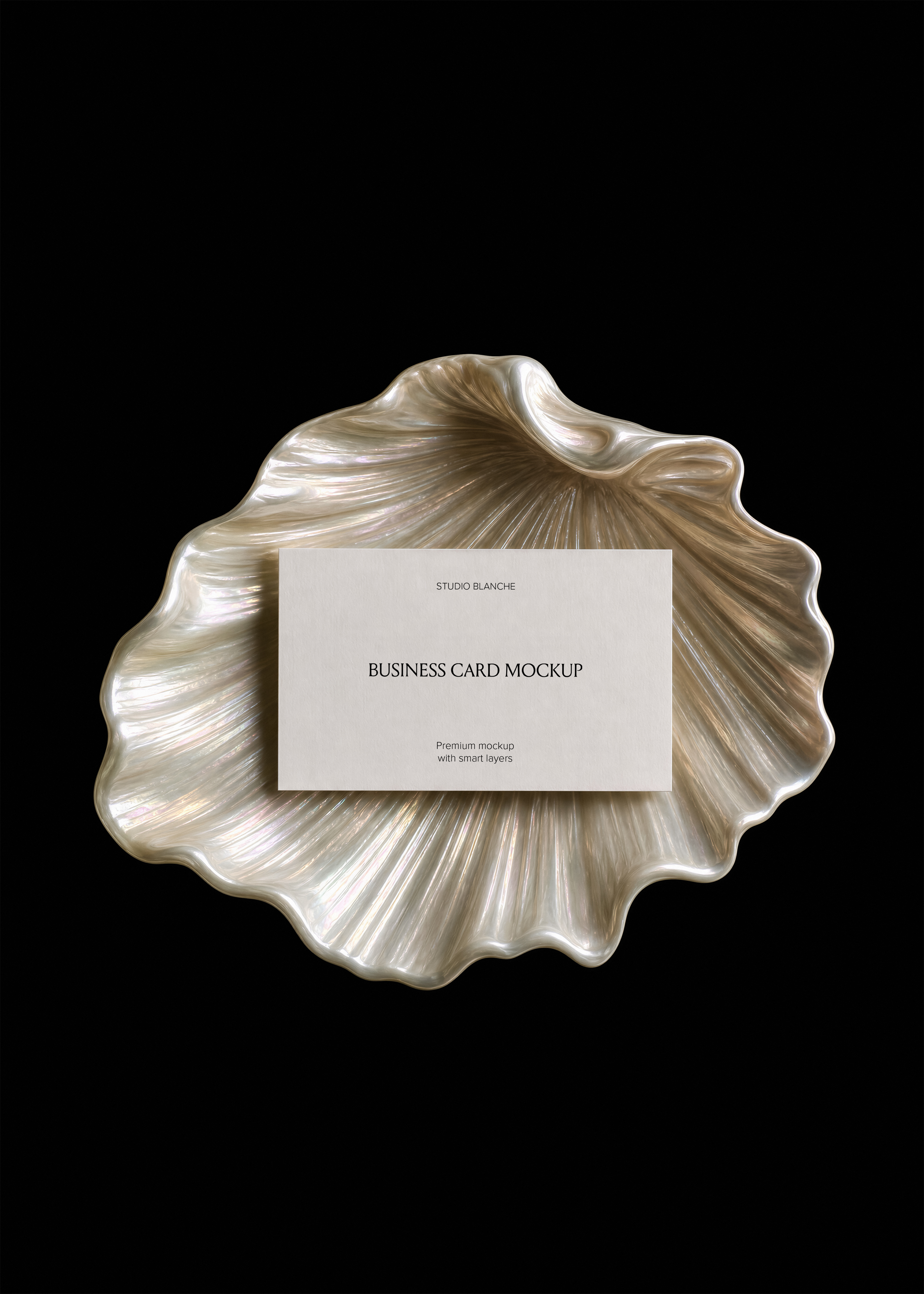 Cream business card with serif logo and script subheading placed on a pearlescent shell dish, black backdrop, top down view
