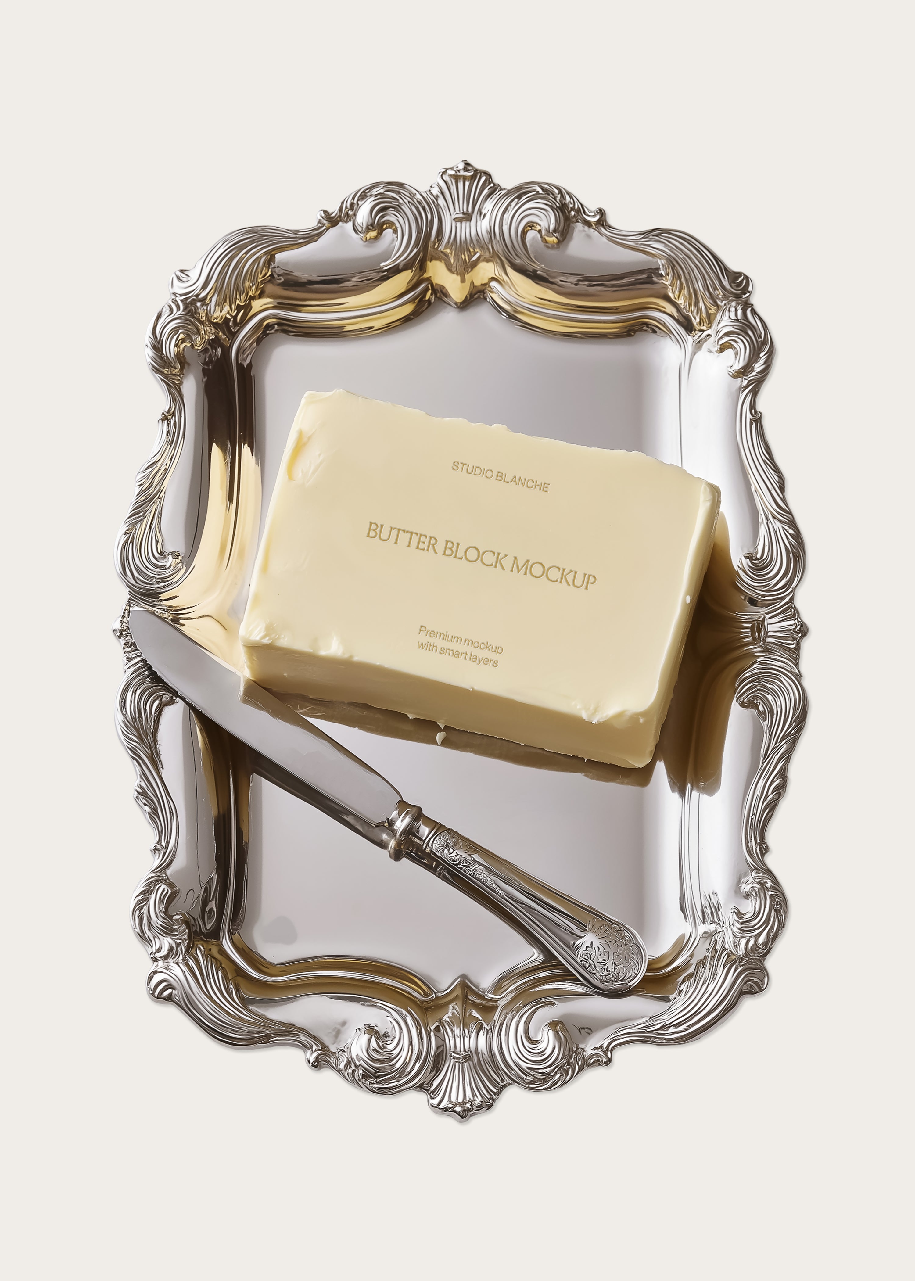 Butter block mockup on polished silver rococo tray with antique butter knife, angled view, gold reflections, cream background