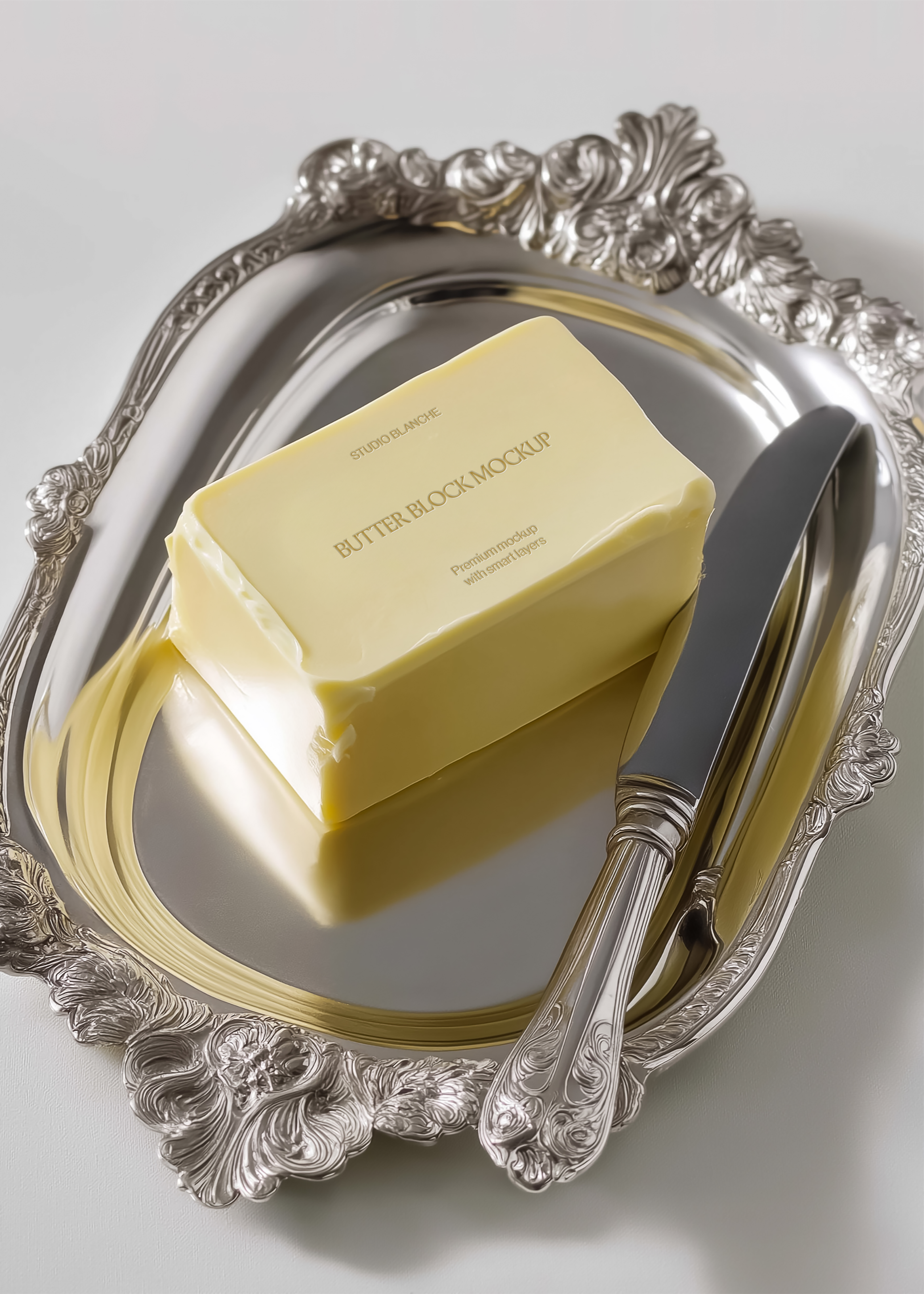 Butter block mockup on decorative silver tray with table knife, overhead angle, soft natural daylight, white background