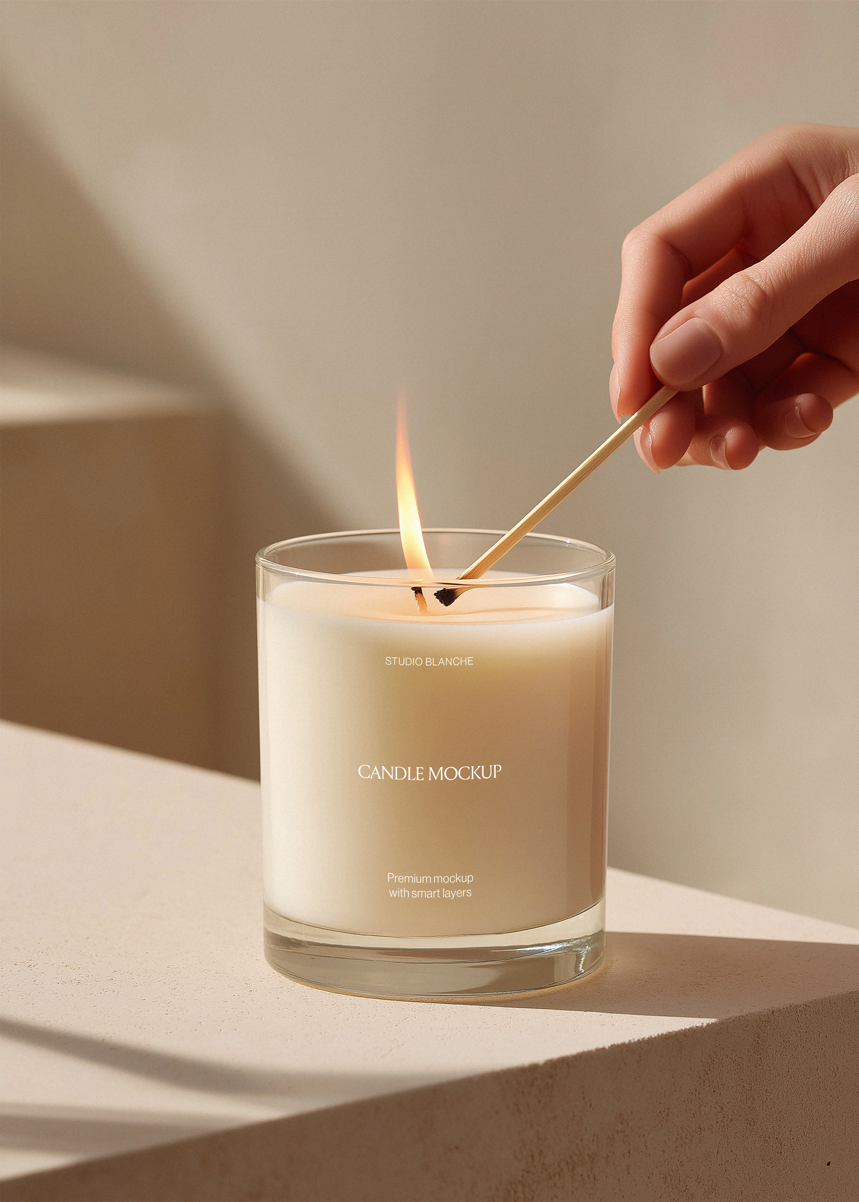 Studio Blanche candle jar mockup with hand holding lit match over cream wax, warm editorial lifestyle scene
