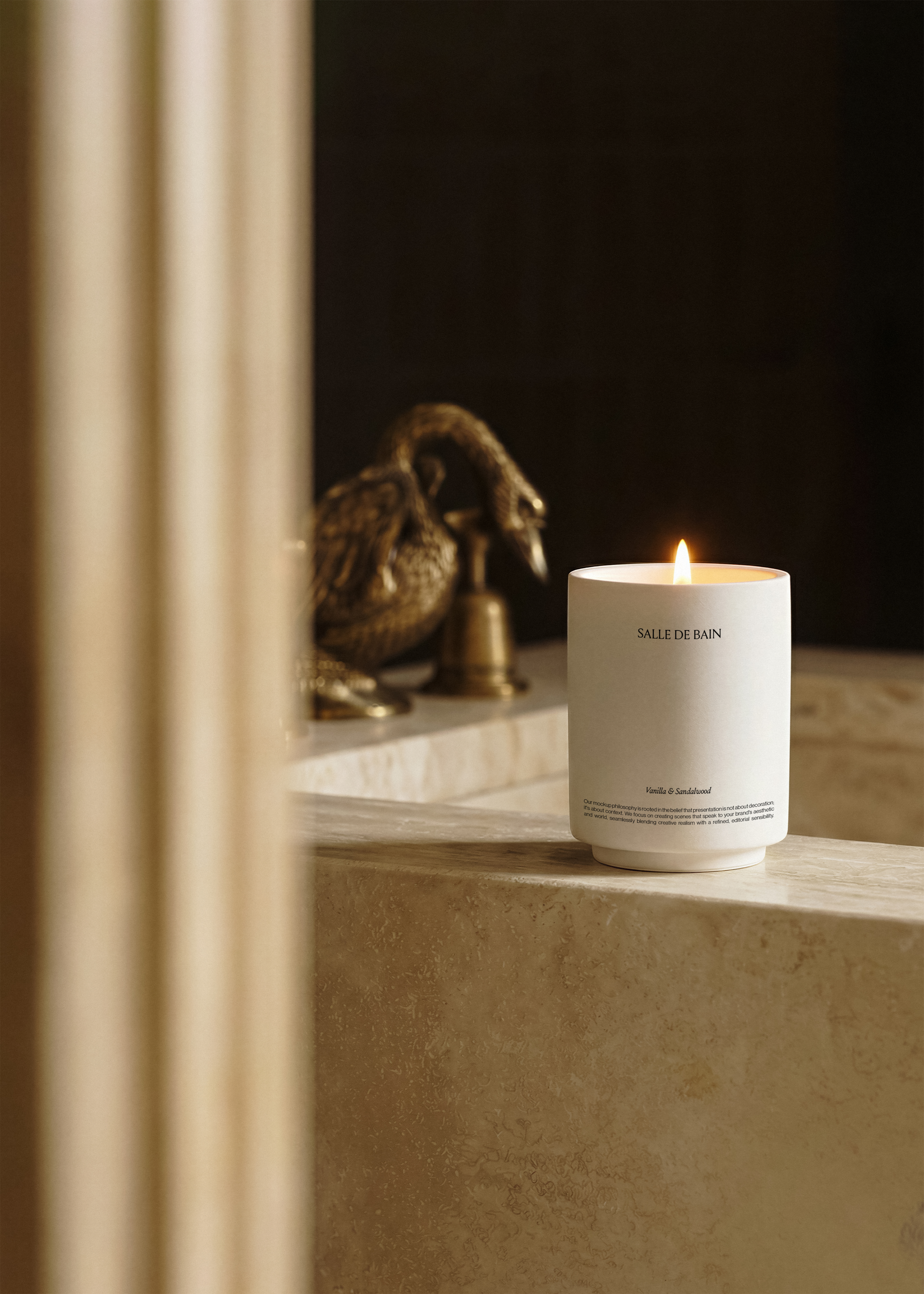 Candle jar mockup on a travertine bathtub edge in warm light, brass swan tap and mirror behind, minimal editorial styling