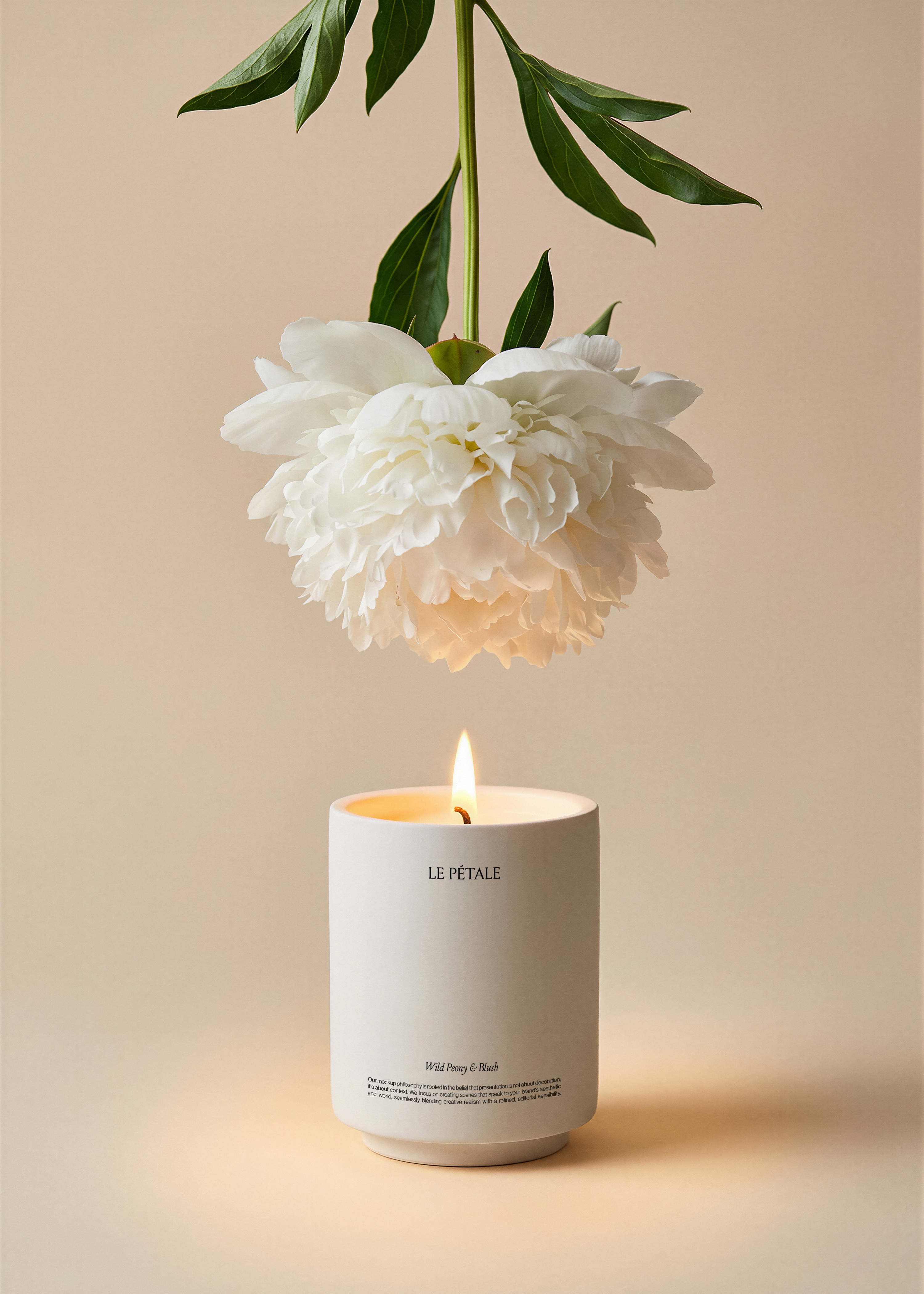 Matte ceramic candle jar mockup with printed label, lit wood wick, white peony and tropical leaf stem overhead, warm sand backdrop