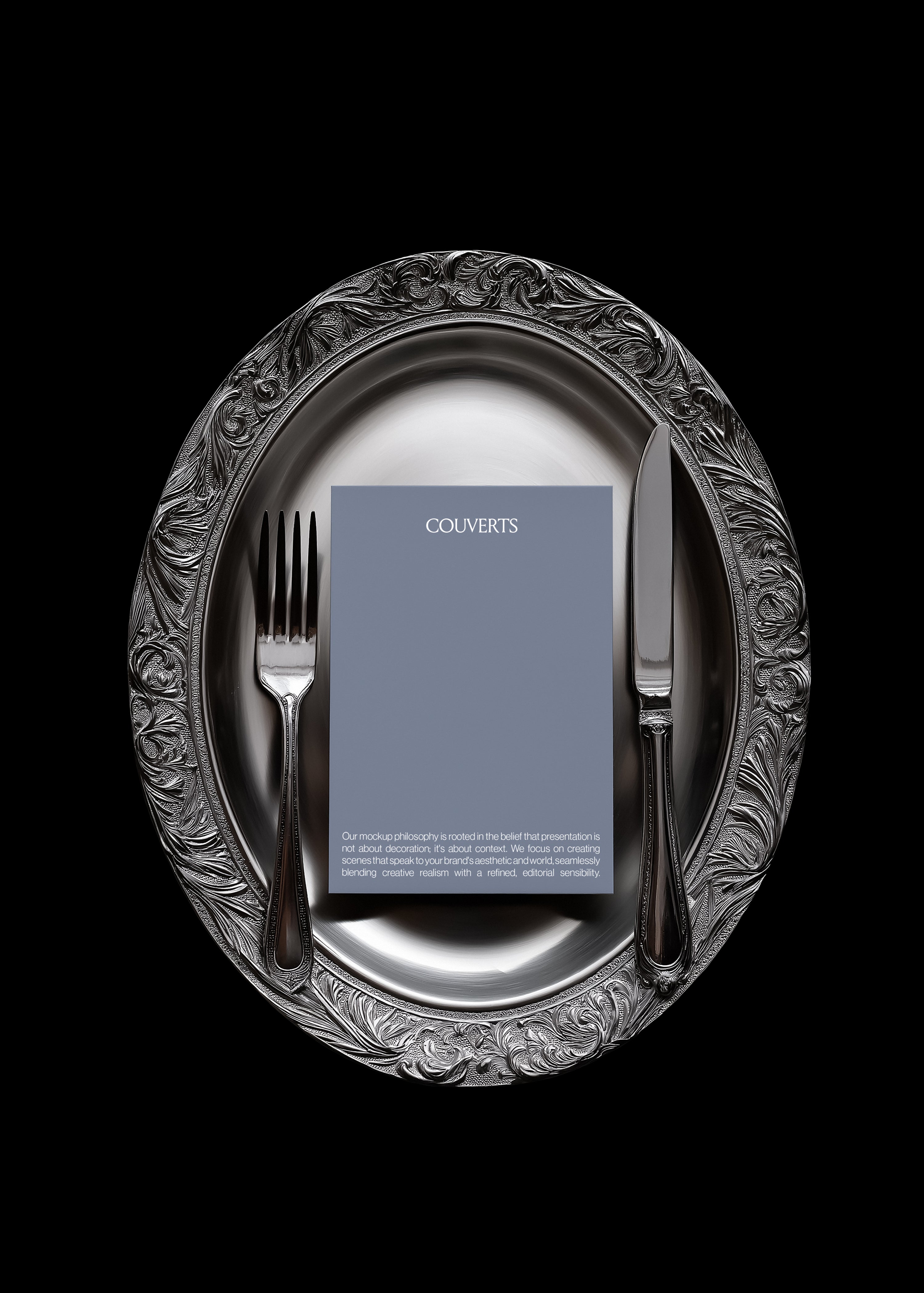 Portrait card mockup on oval silver charger with acanthus scroll engraving and fork and knife either side, black background