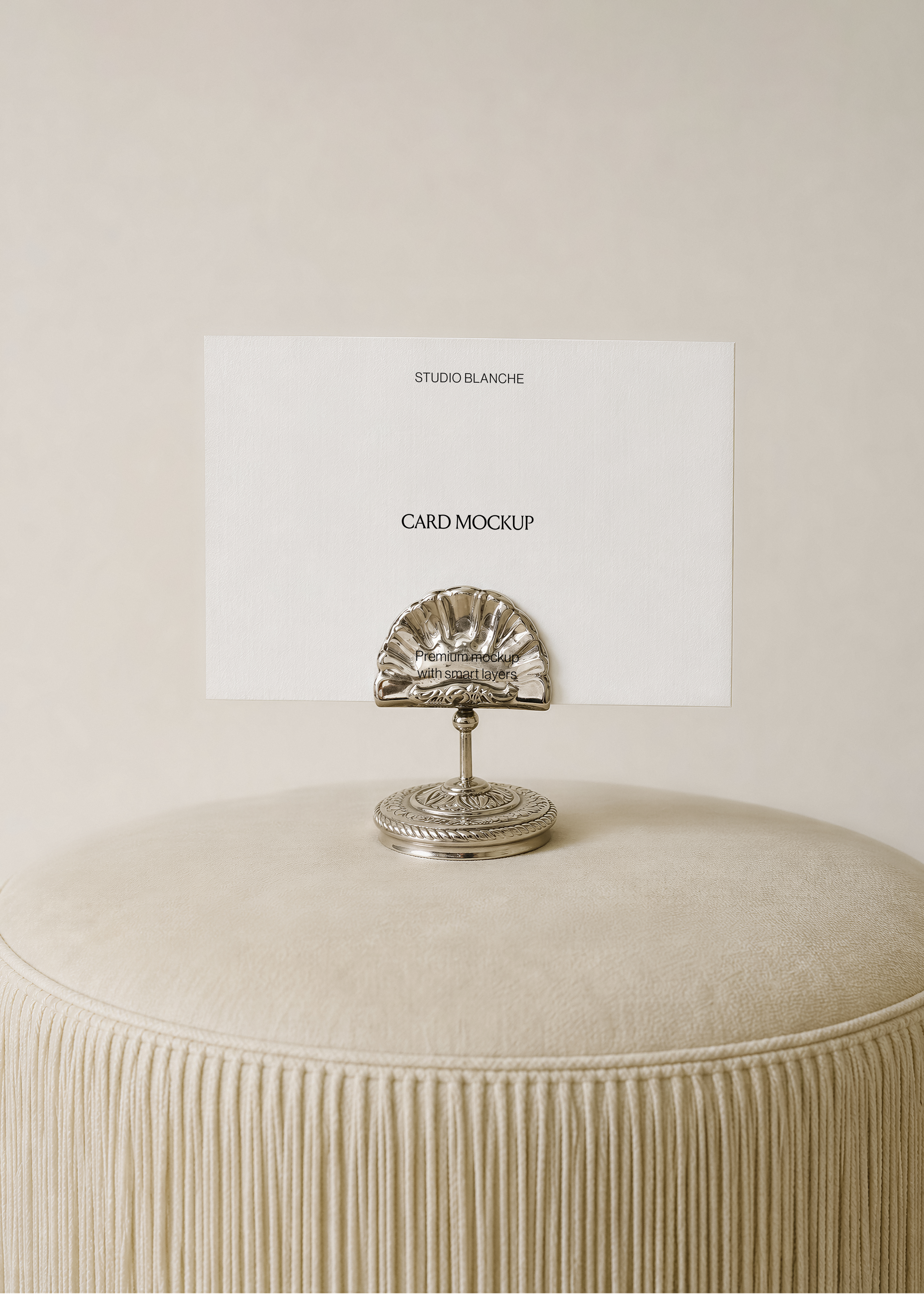 Card mockup detail of a white card clipped in a polished silver holder with fluted shell top and engraved round base