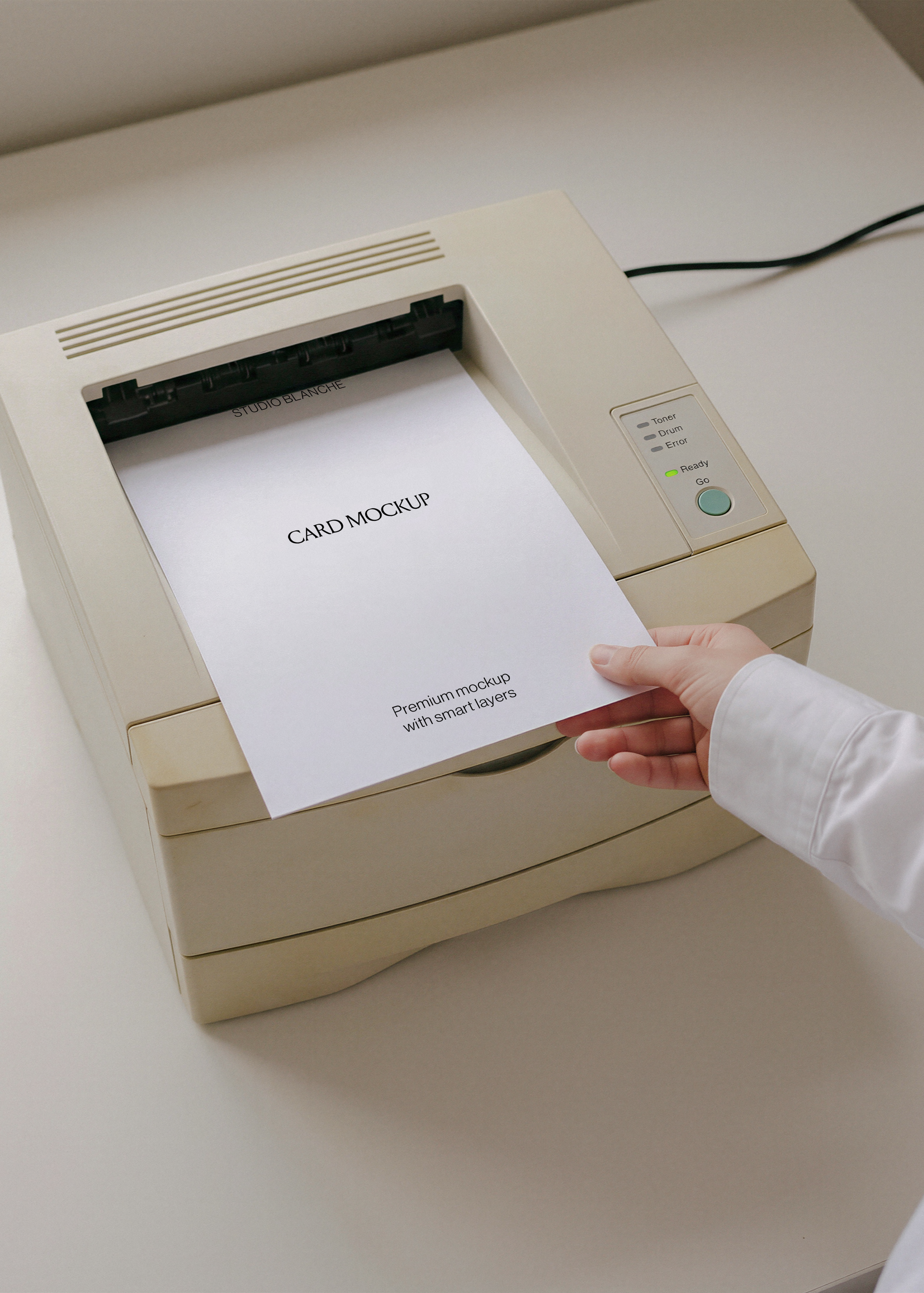 Blank A4 letterhead emerging from retro beige laser printer, Ready light on, hand resting on sheet, pale desk surface