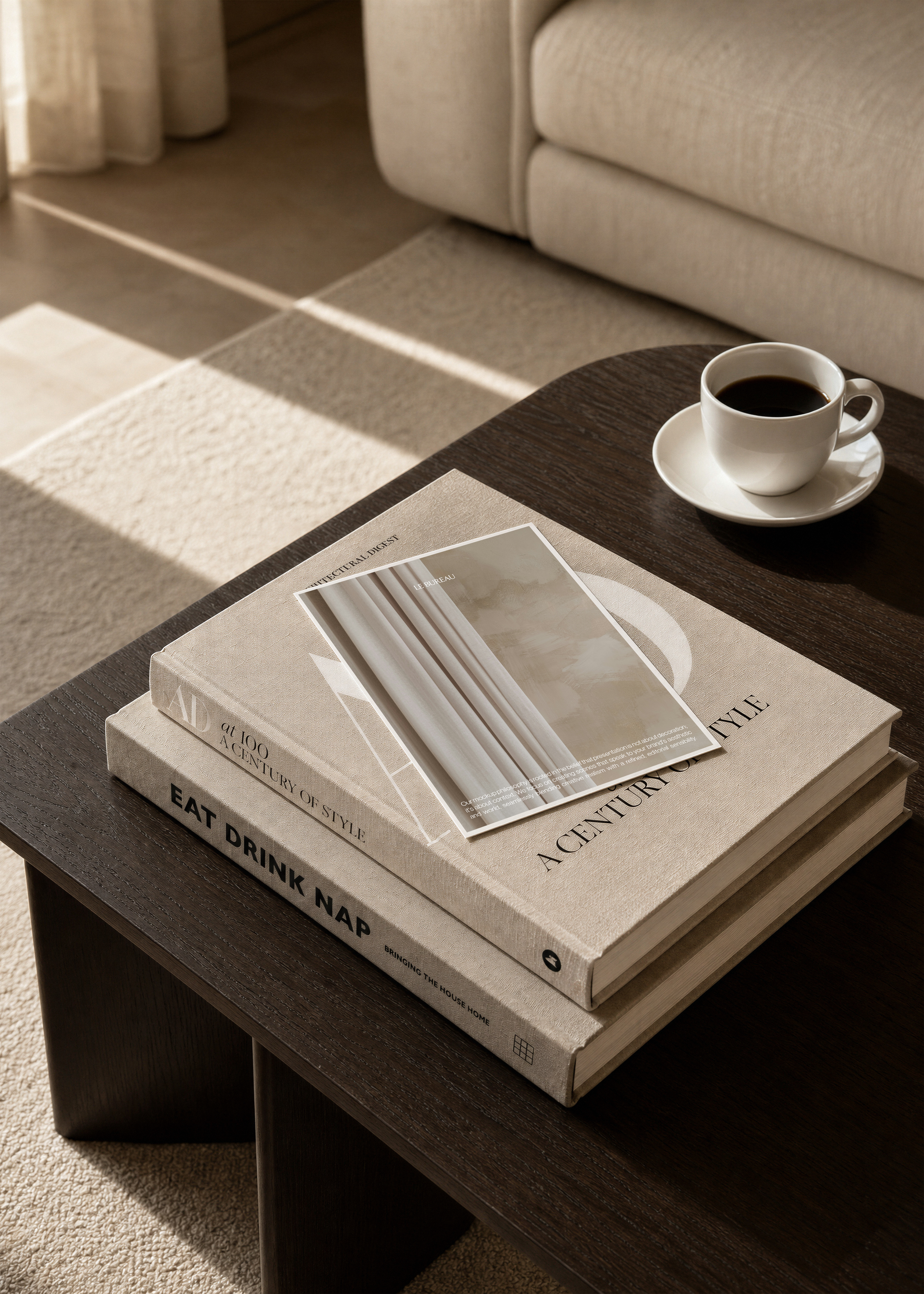 Card mockup resting on stacked beige coffee table books beside espresso cup on dark wood table, sunlit lounge