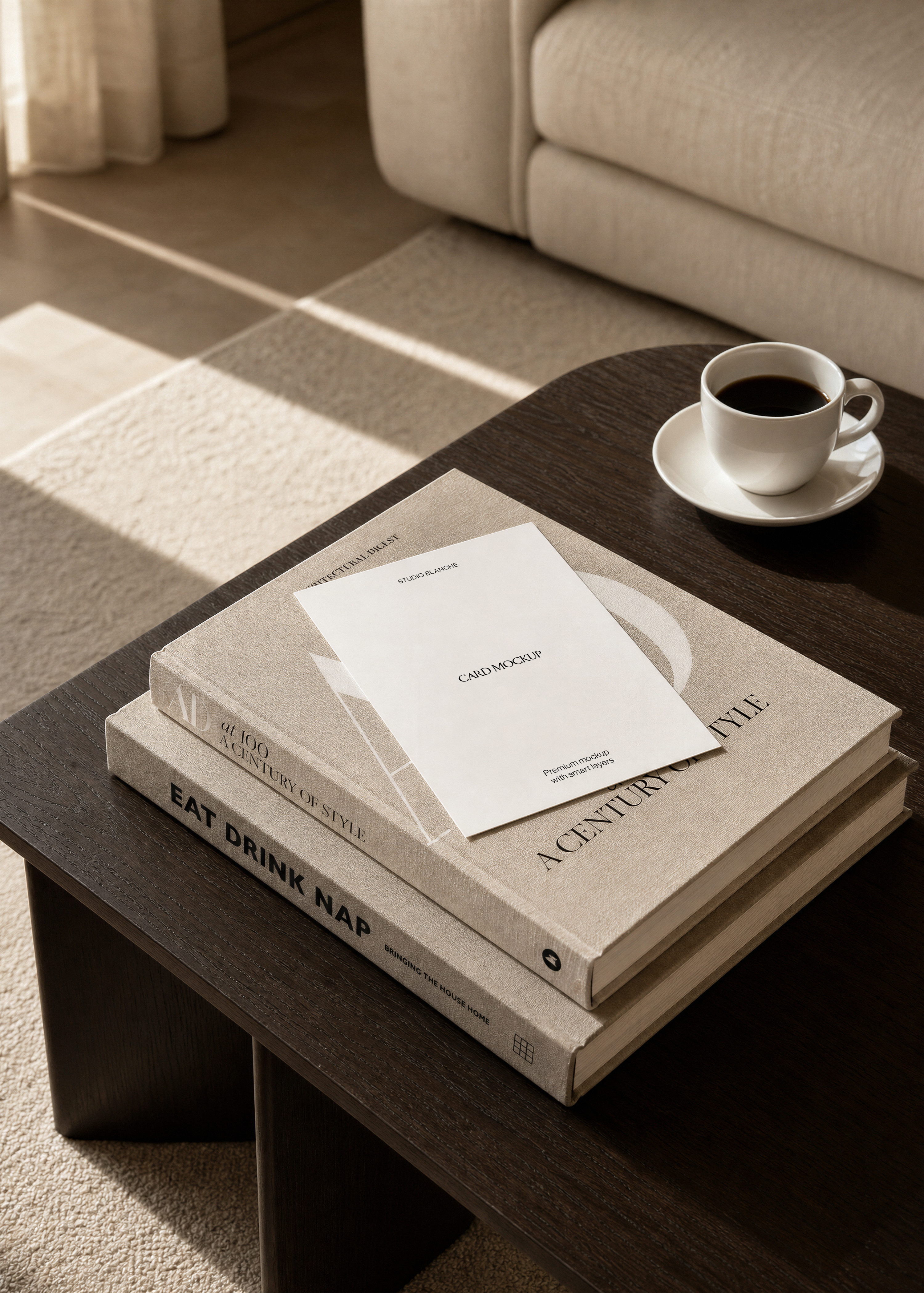 White flat card mockup angled on linen hardback book, window light shadows on rug and cream sofa in background