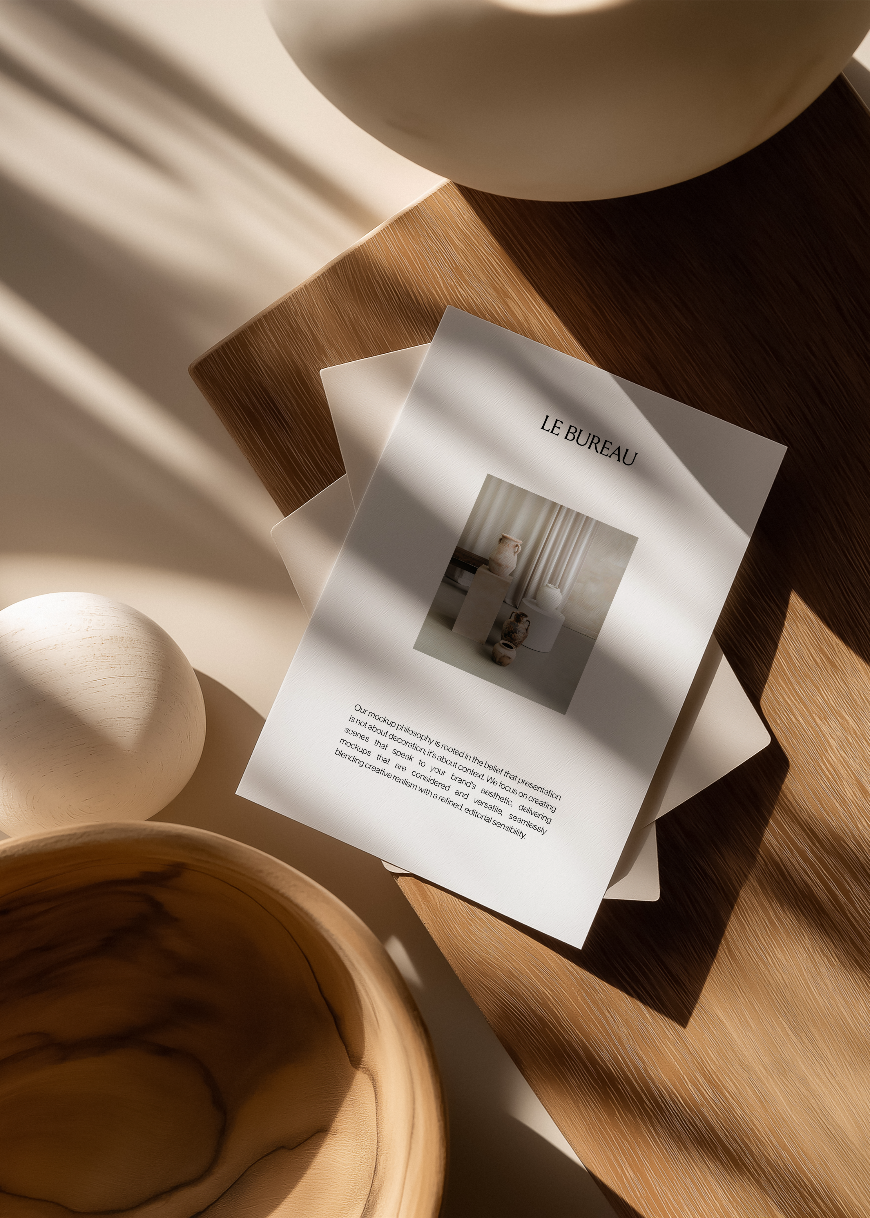 Card mockups displaying Le Bureau branding on pale oak board, sculptural wooden props and strong diagonal window light