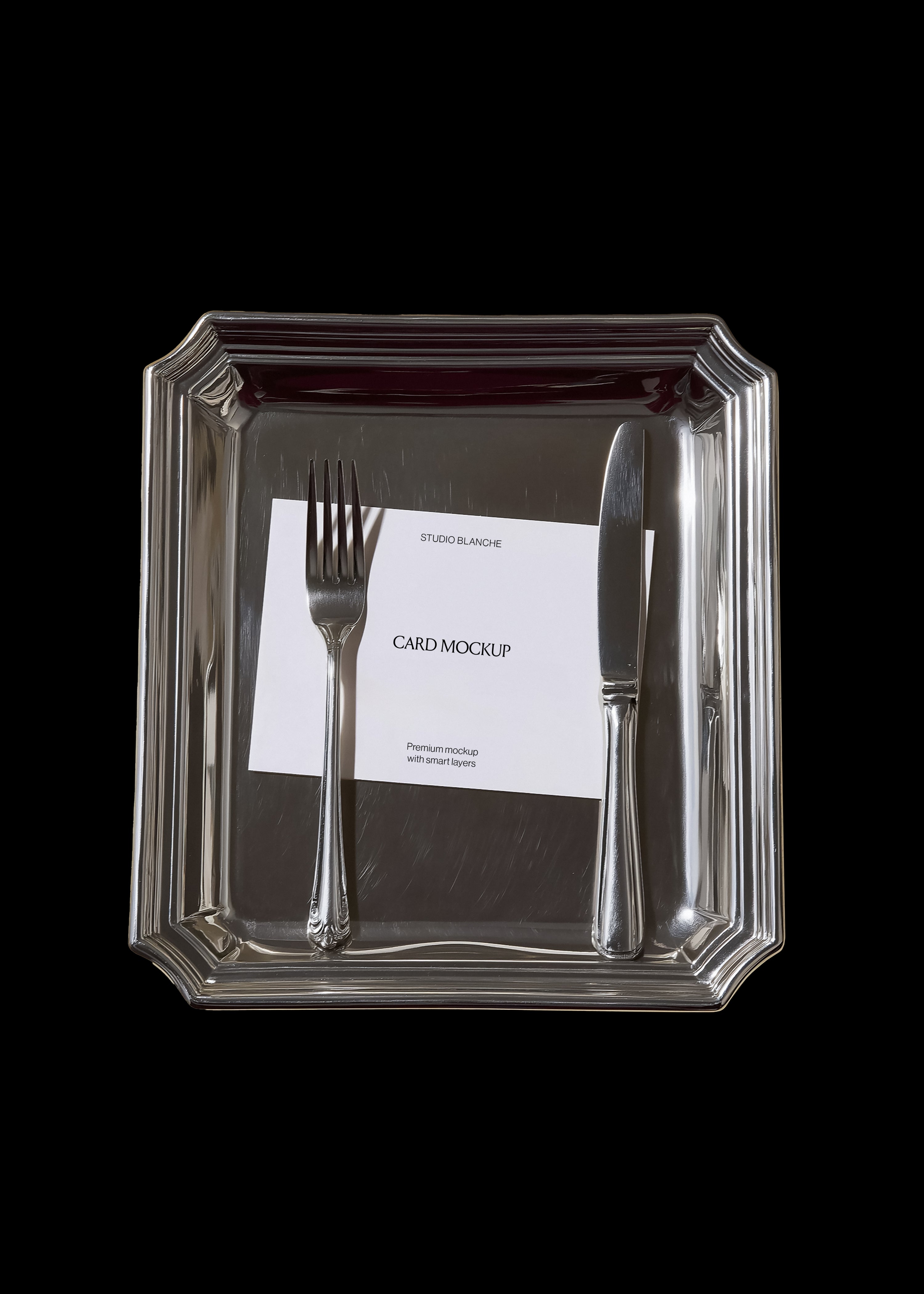 Card mockup detail on mirrored silver tray with mitred corners, fork and knife, white card with black text