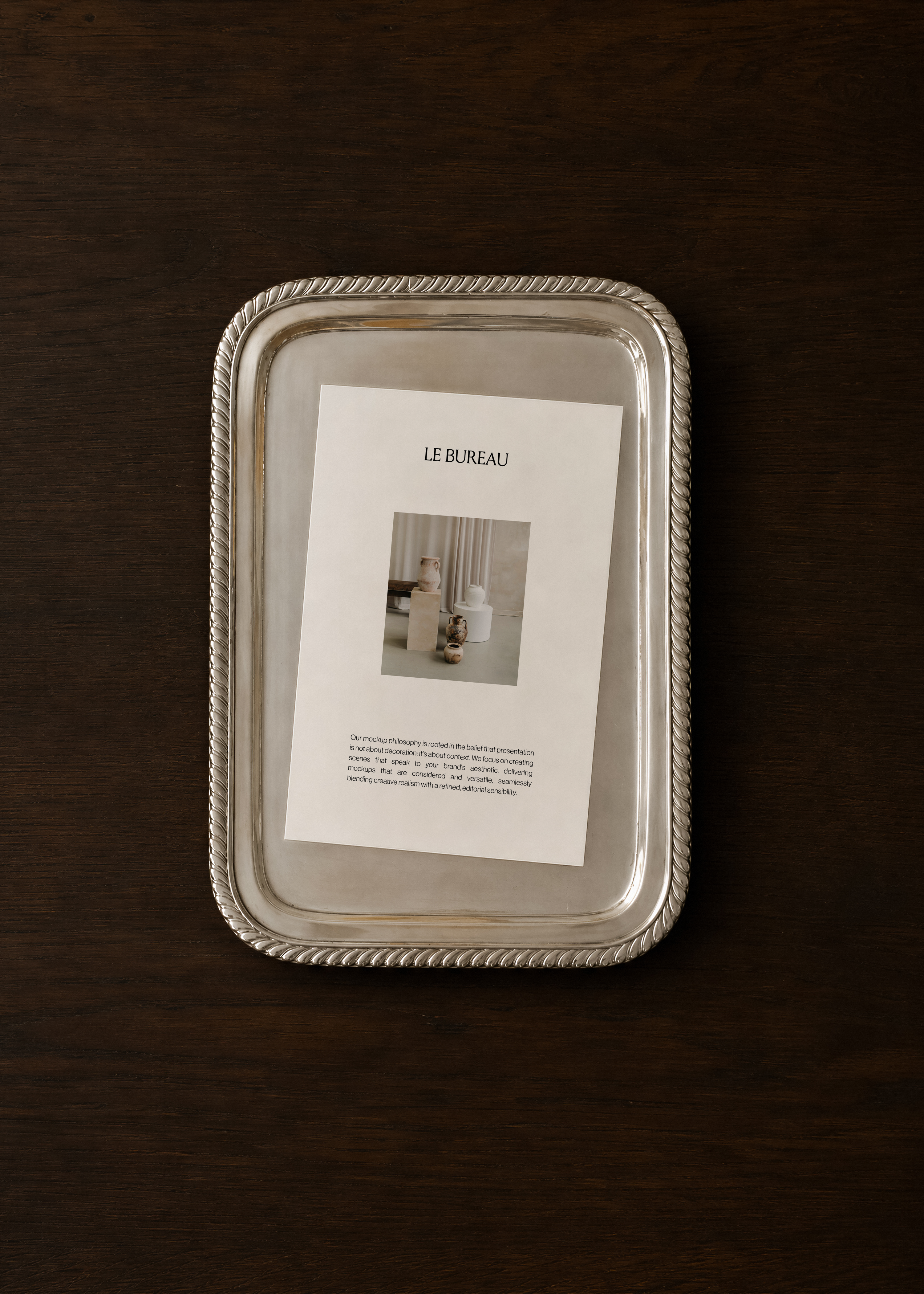 Card mockup displaying Le Bureau branding on polished silver rope tray, dark walnut surface overhead scene