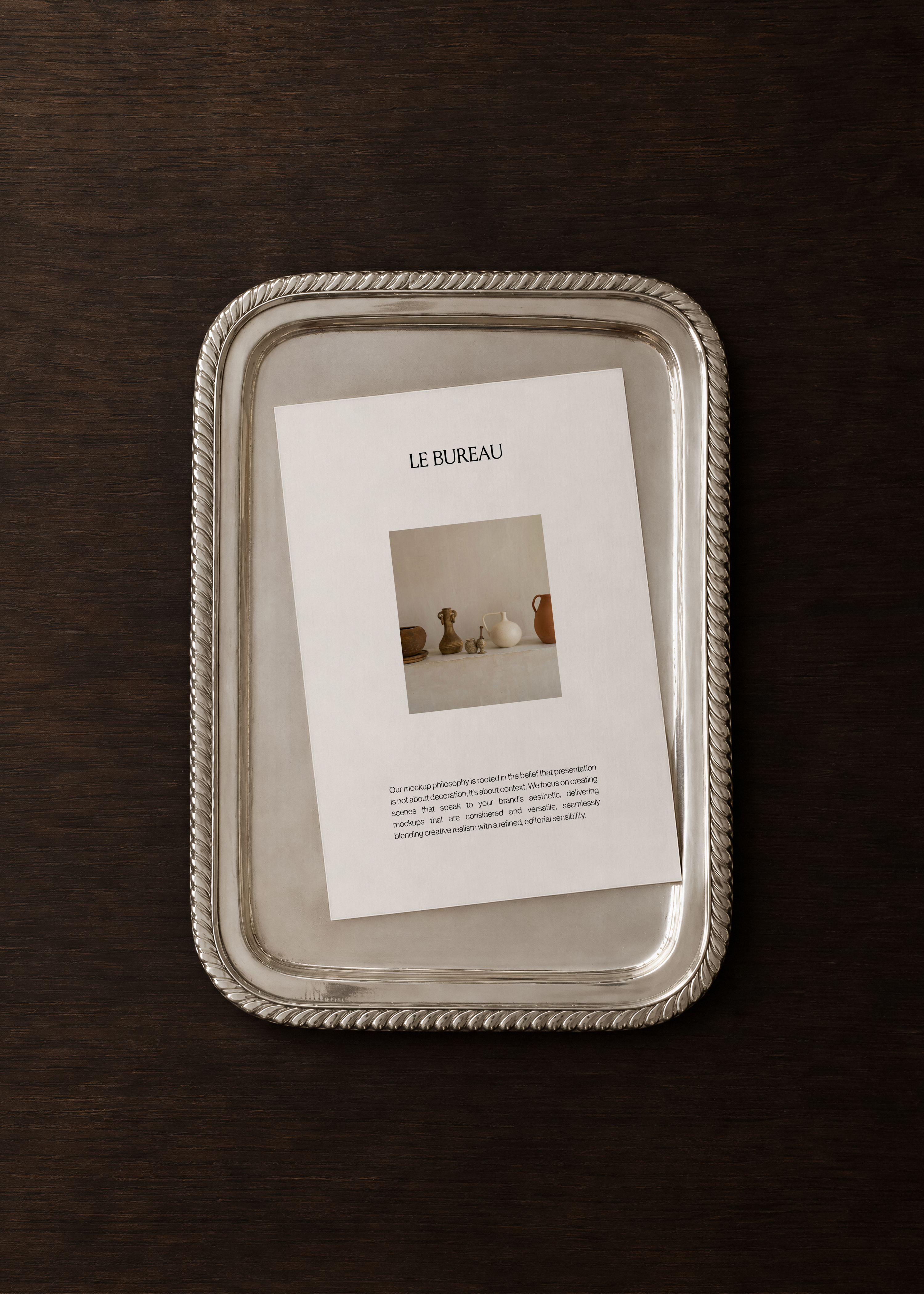 Card mockup displaying Le Bureau branding on silver rope tray, dark walnut surface, overhead editorial scene
