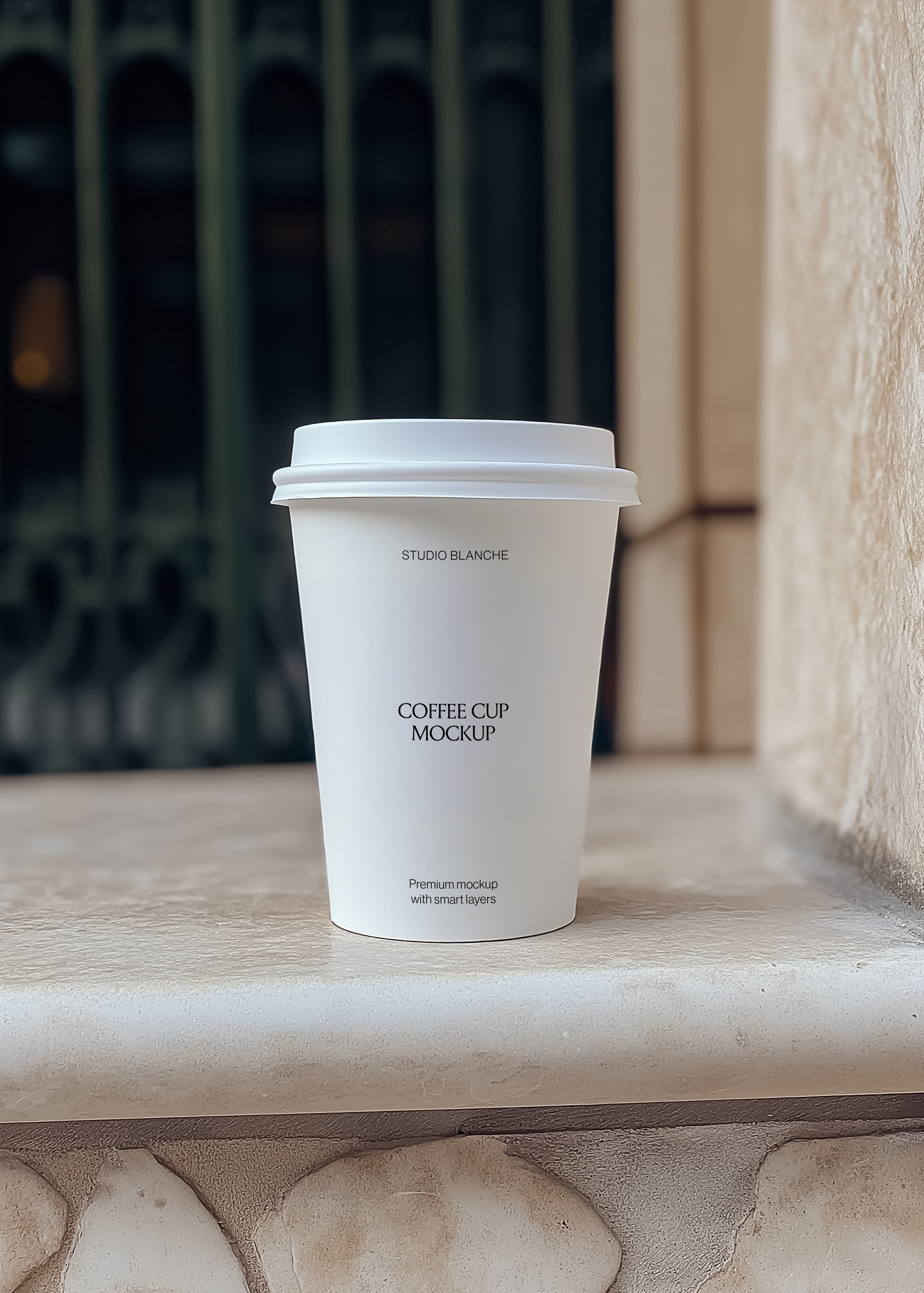 Coffee cup mockup front on, cream paper cup with black café label text and white lid, warm sunlight on stone ledge