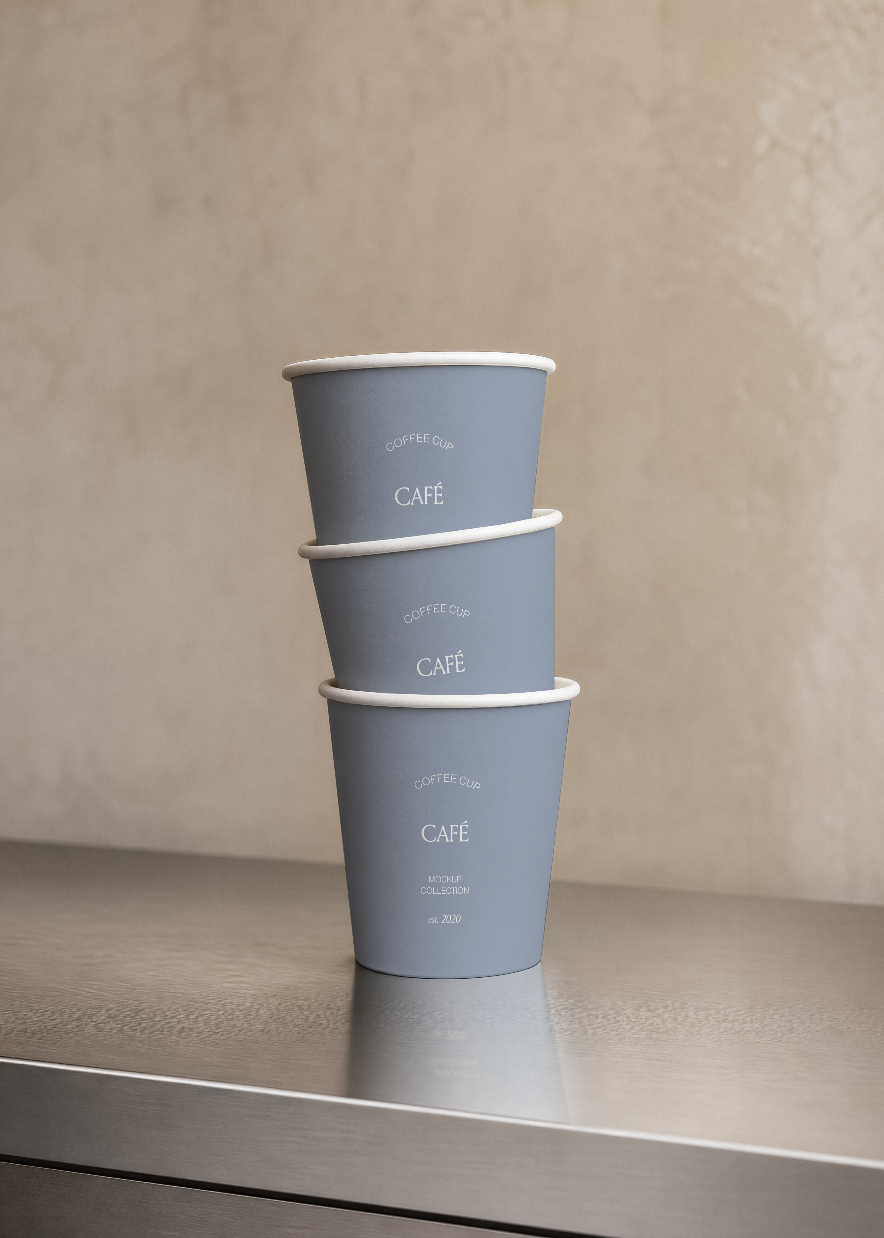 Three stacked coffee cup mockups in dove grey on brushed steel counter with soft reflection, plain warm-toned wall