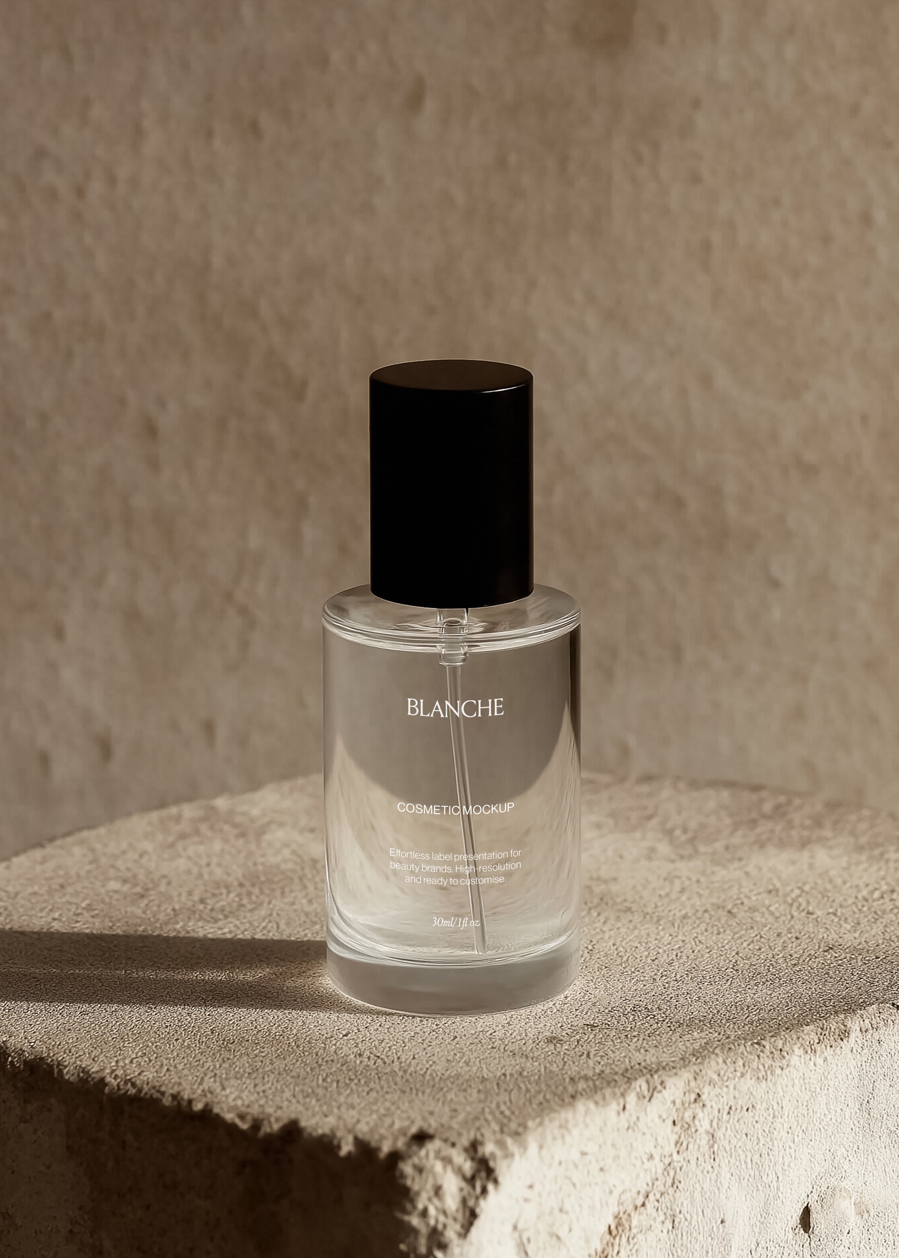 Clear glass cosmetic spray bottle mockup with tall black cap on a plaster pedestal in warm, hard sunlight