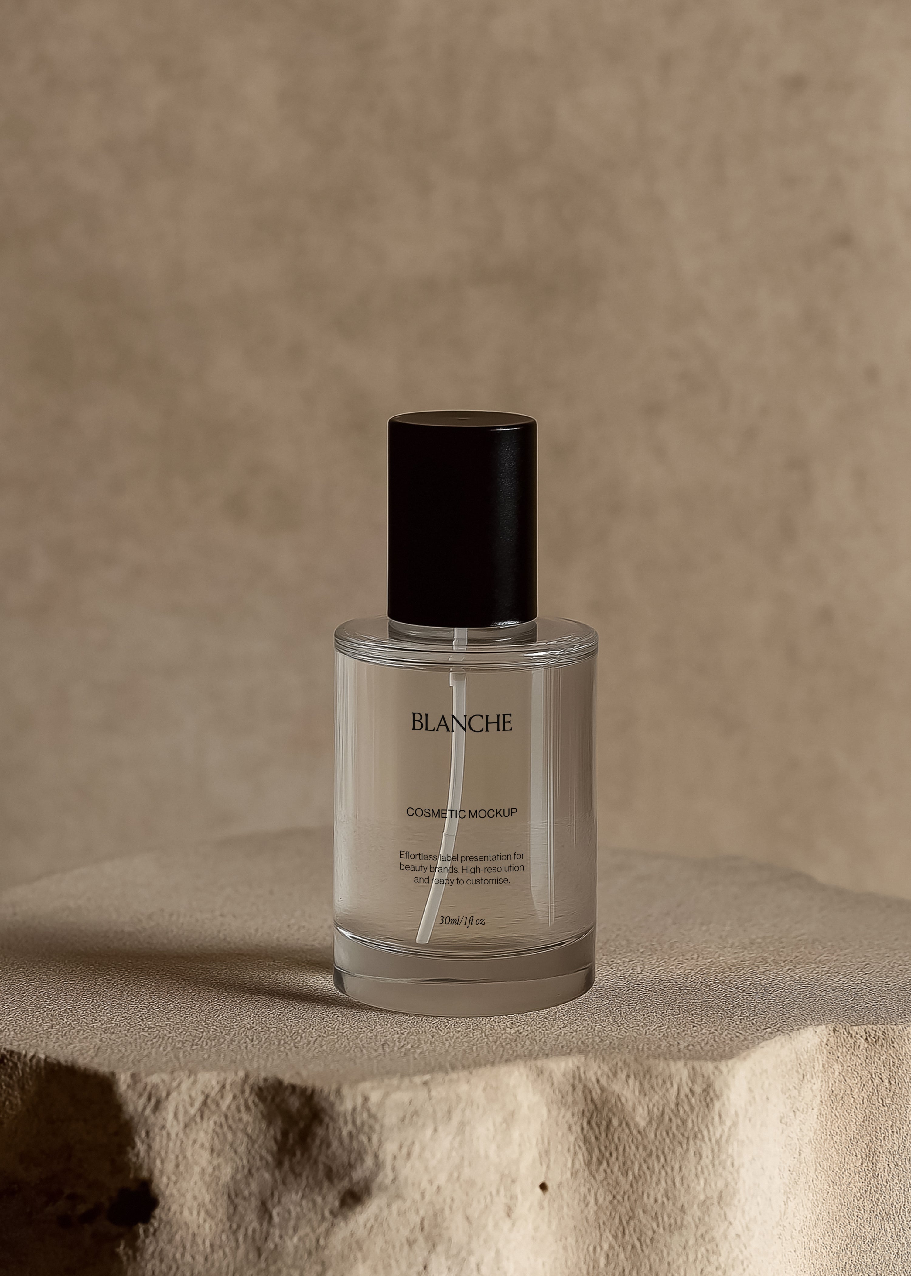 Clear glass cosmetic spray bottle mockup with tall black cap on a raw stone plinth, warm plaster wall behind