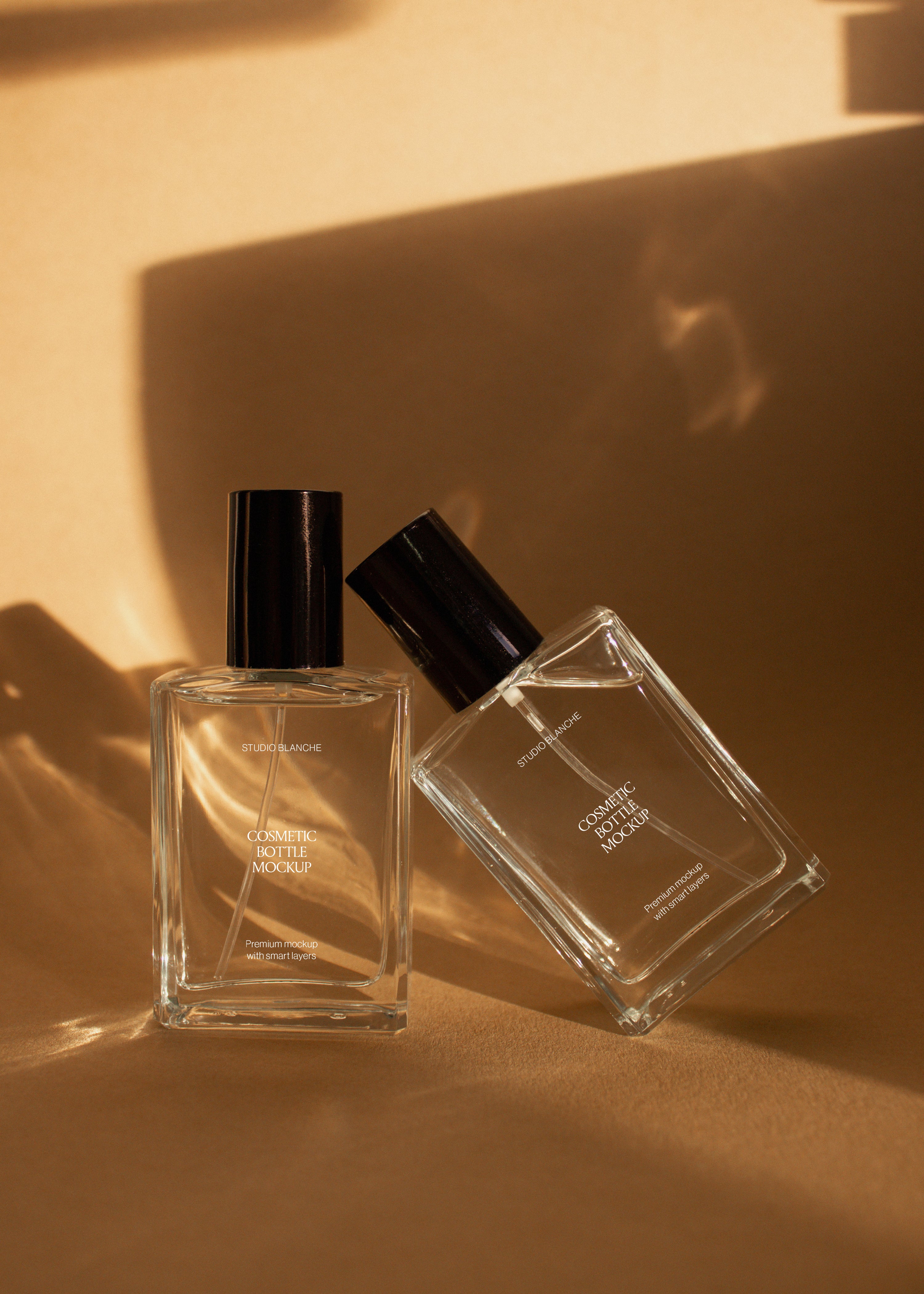 Upright and angled cosmetic bottle mockups in clear glass on sandstone backdrop, warm amber light and long soft shadow