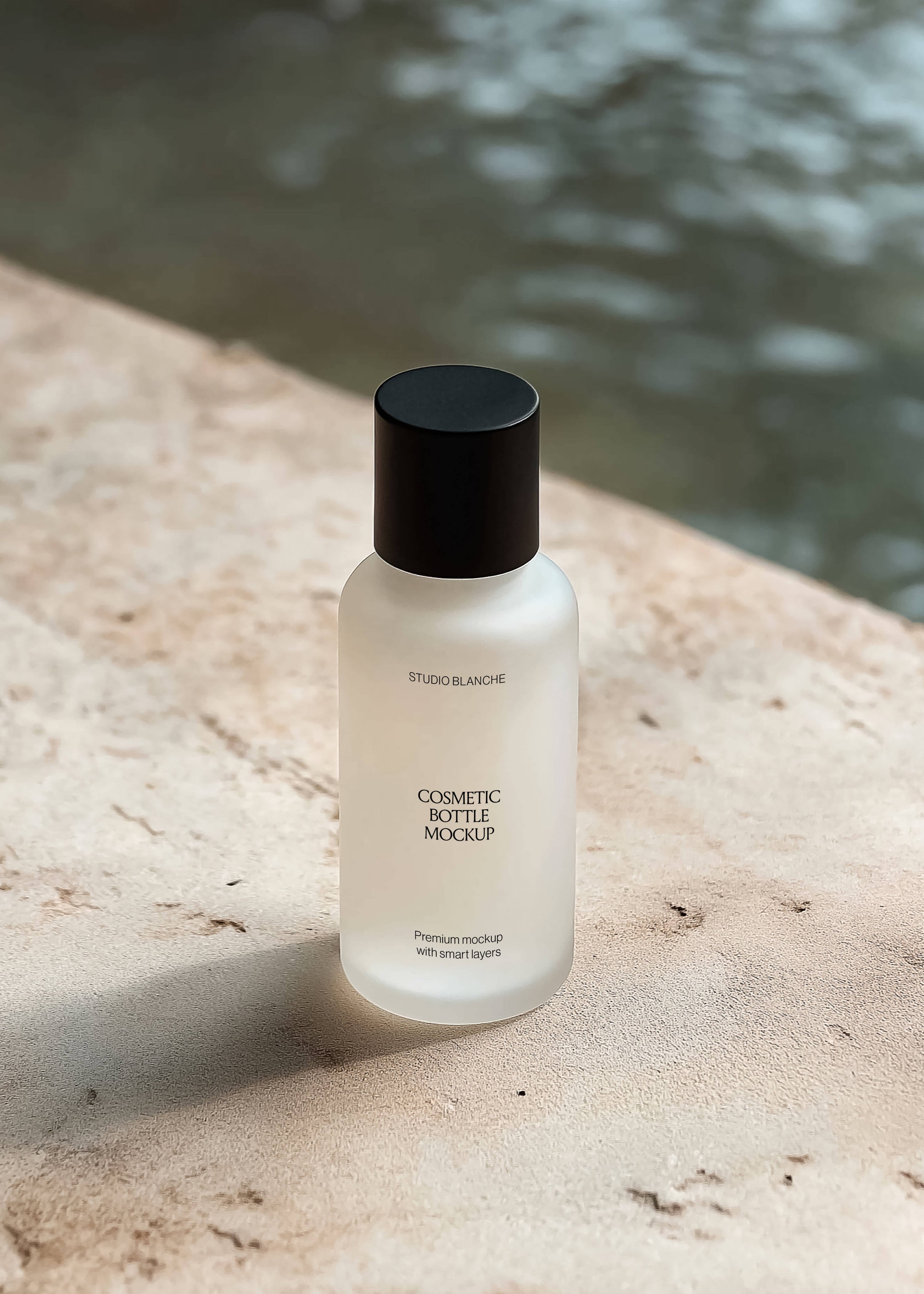 Frosted cosmetic bottle mockup with serif label and black cap on travertine by a pool, warm coastal light