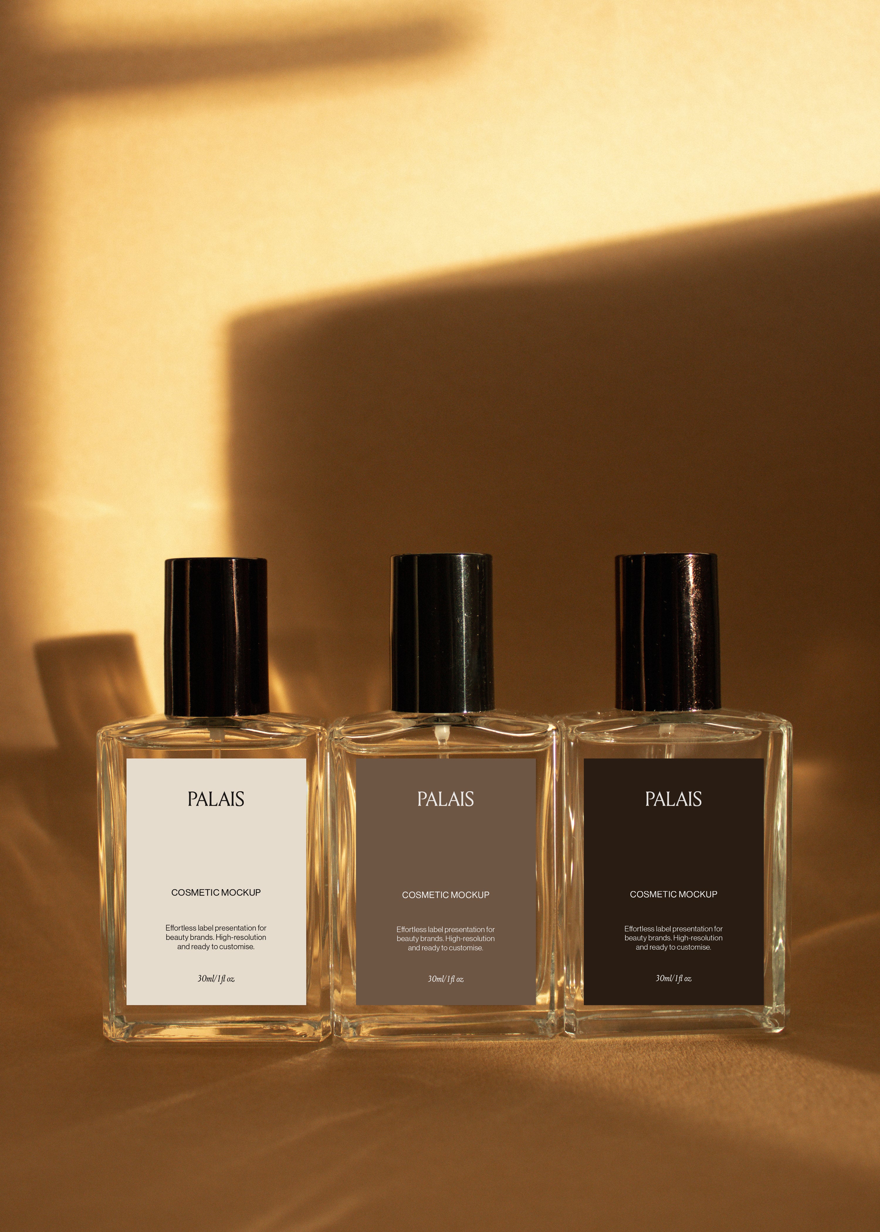 Three clear glass cosmetic bottle mockups with black caps in a row on warm sandstone surface, editorial styling