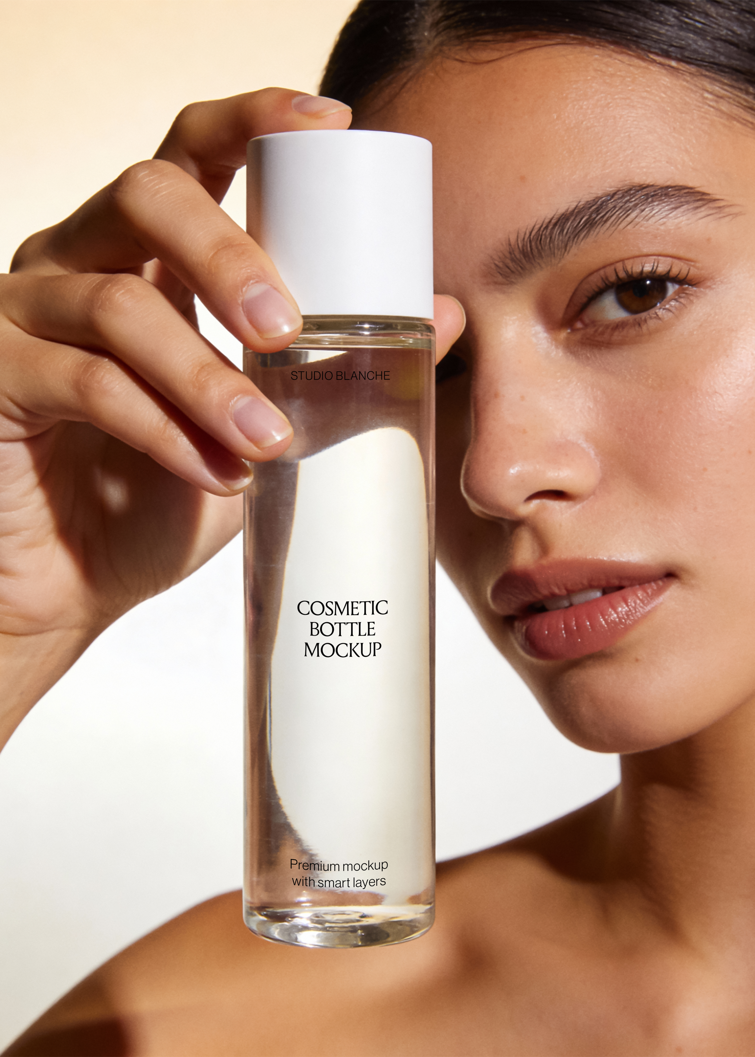 Clear glass cosmetic bottle mockup with minimal serif label and white cap, warm editorial beauty scene