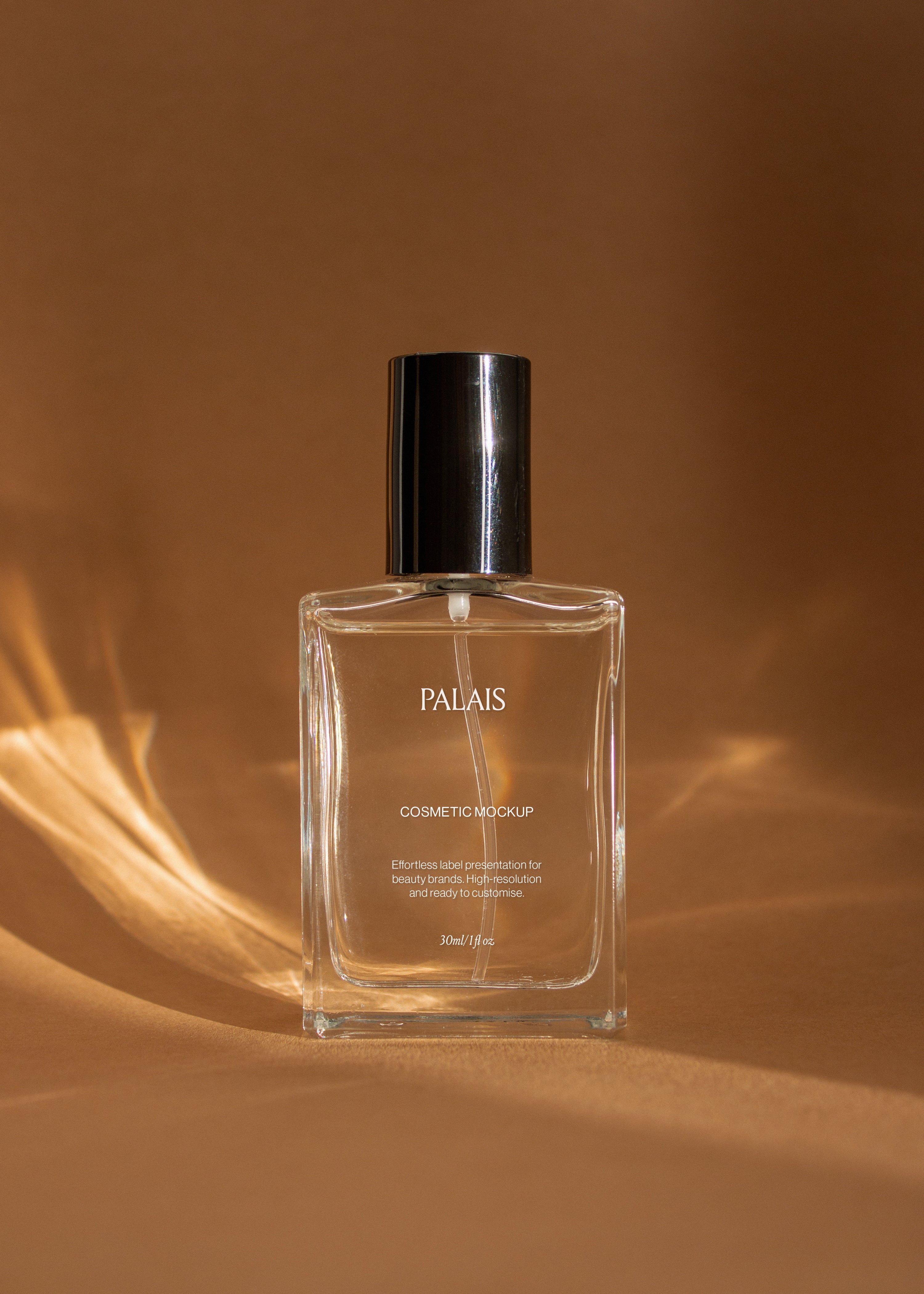 Single upright glass cosmetic bottle mockup with black cap backlit in warm amber light on sandstone surface
