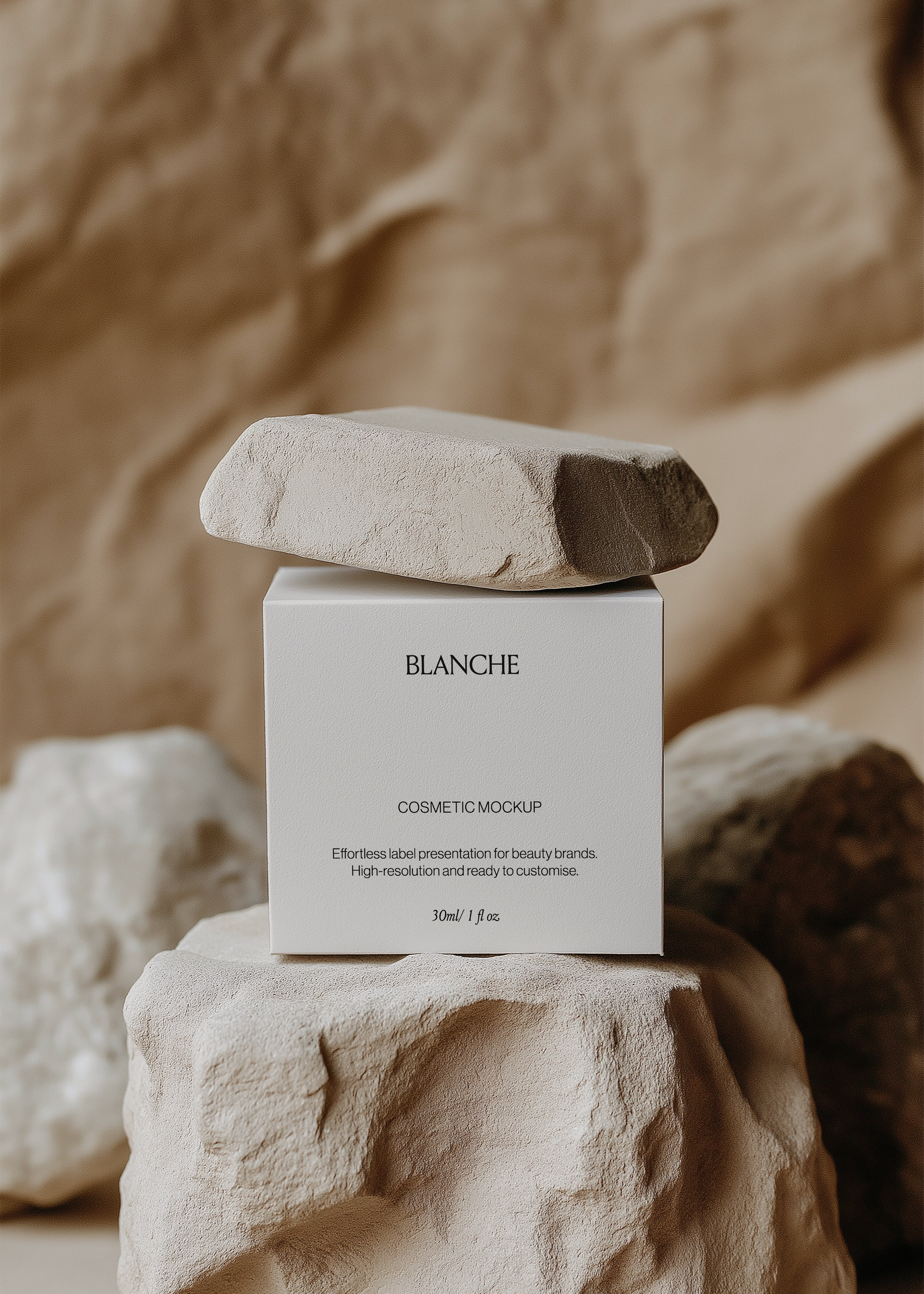 Square white cosmetic box mockup on a sandstone rock with a flat stone balanced on top against a warm draped backdrop