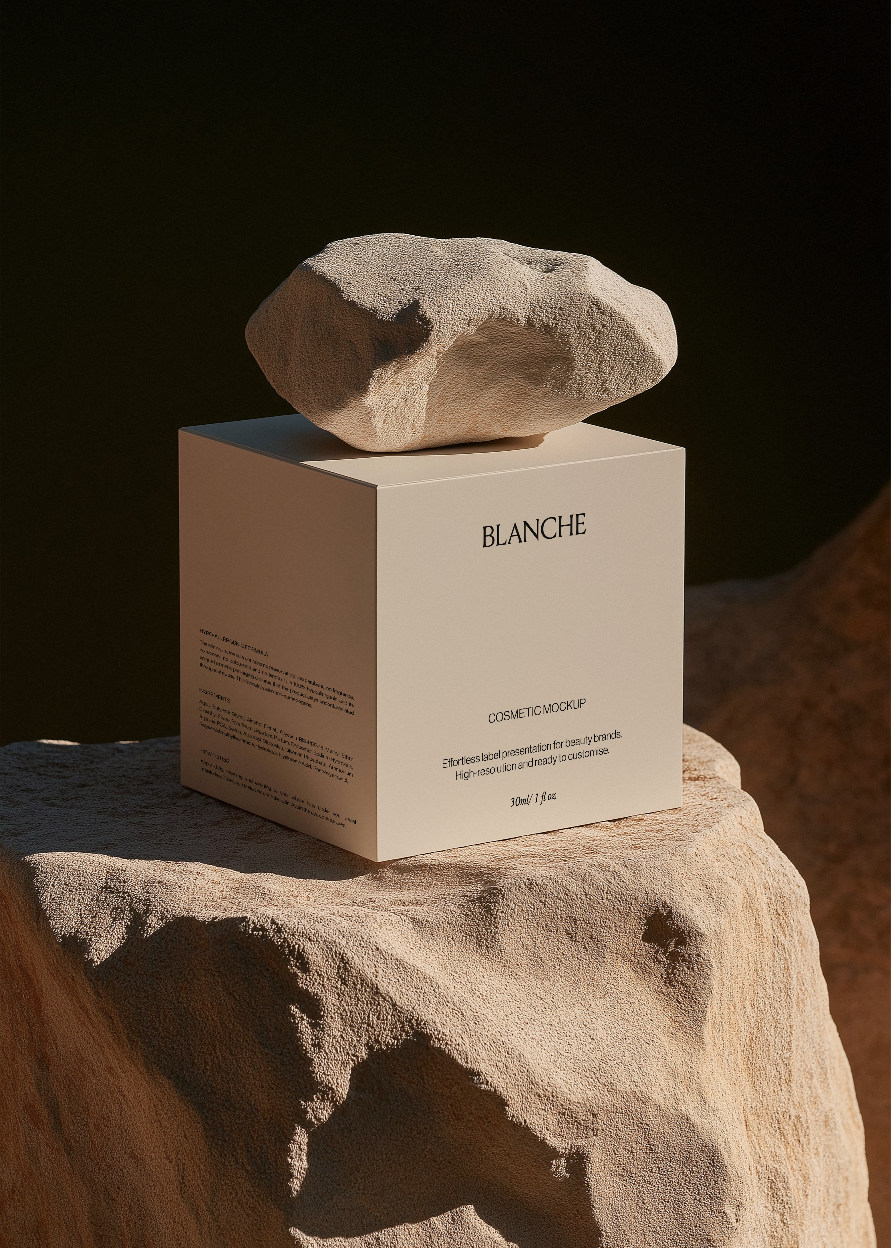 White cosmetic box mockup on a sunlit sandstone rock with a rough stone resting on top against a dark background
