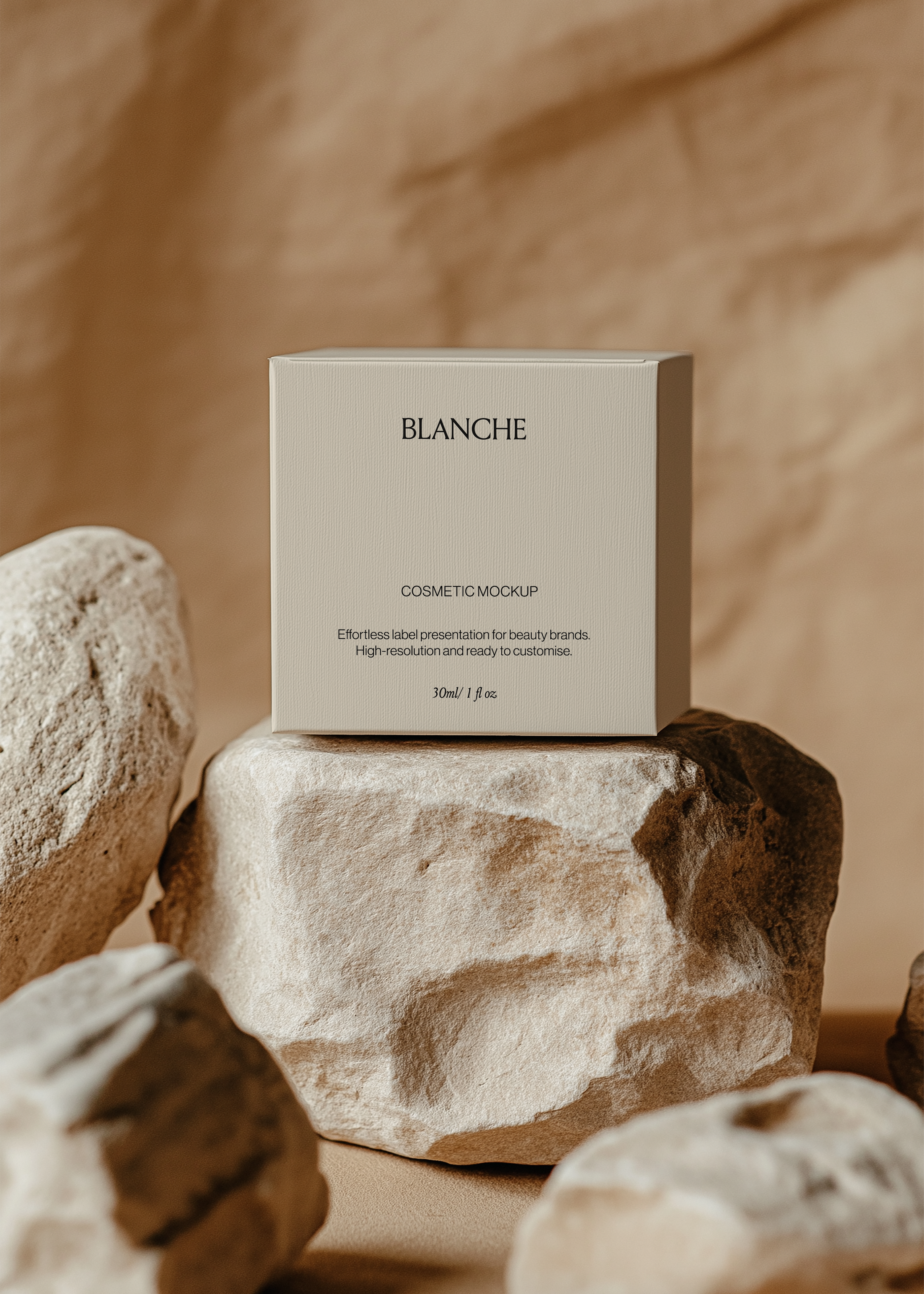 Square white cosmetic box mockup resting on a large sandstone rock among pale boulders against a warm textured backdrop