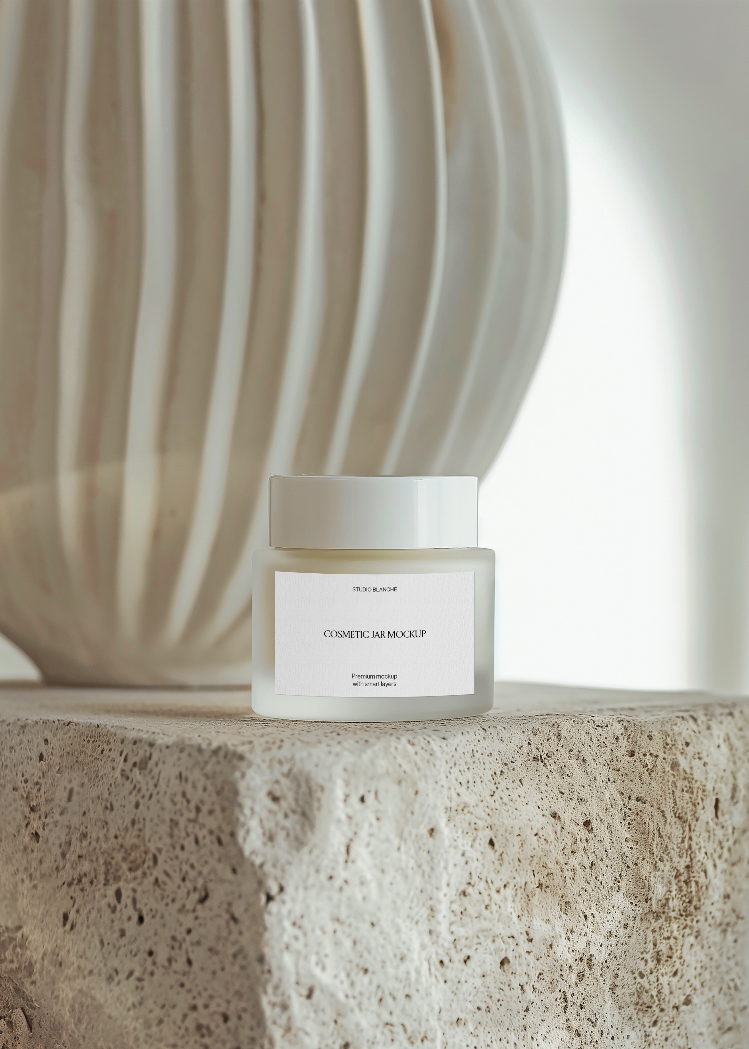 Frosted cosmetic jar mockup on textured stone beside ribbed cream ceramic vase, warm minimal still life scene