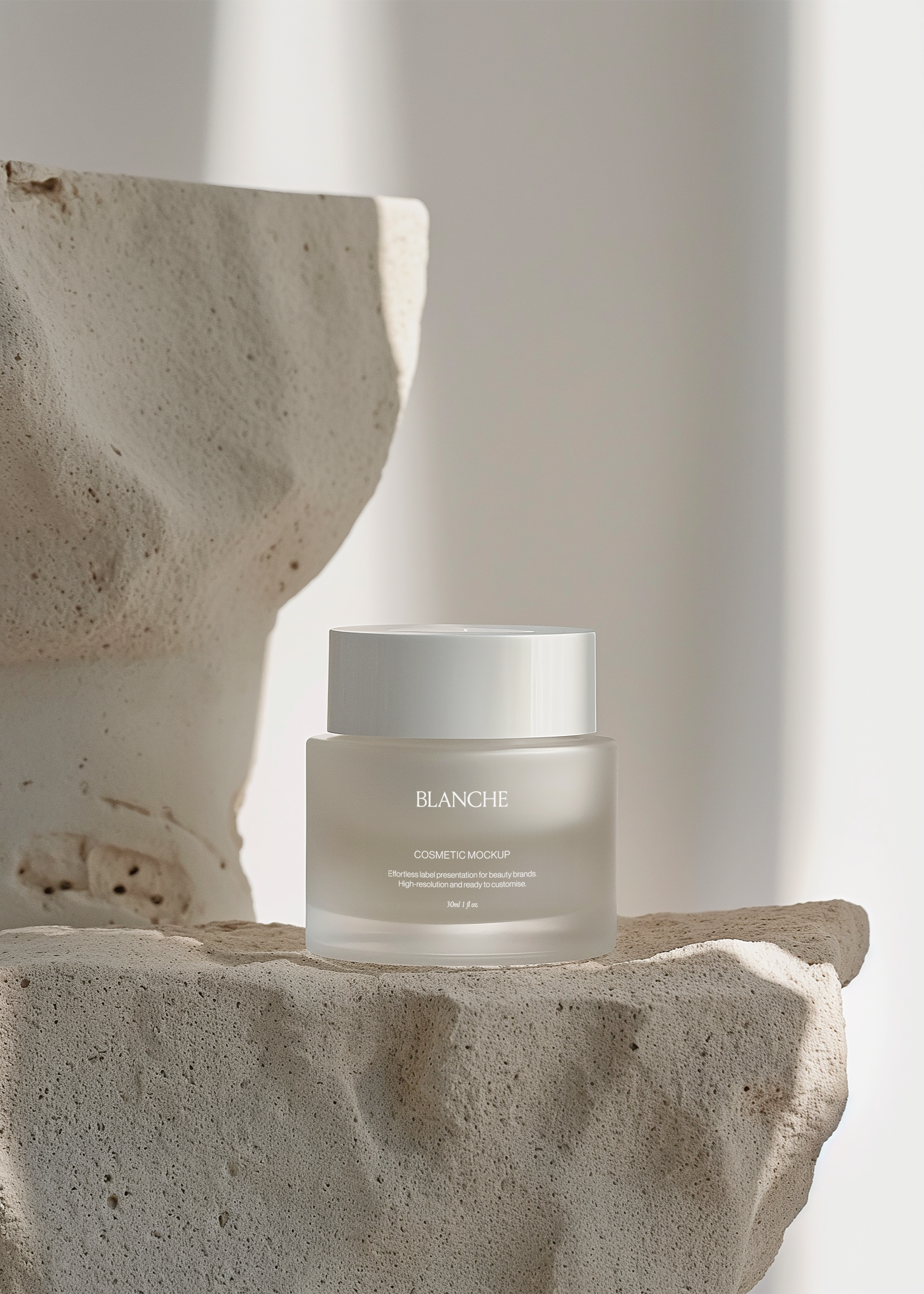 Frosted glass cosmetic jar mockup with glossy white lid on rough travertine ledge beside broken stone form