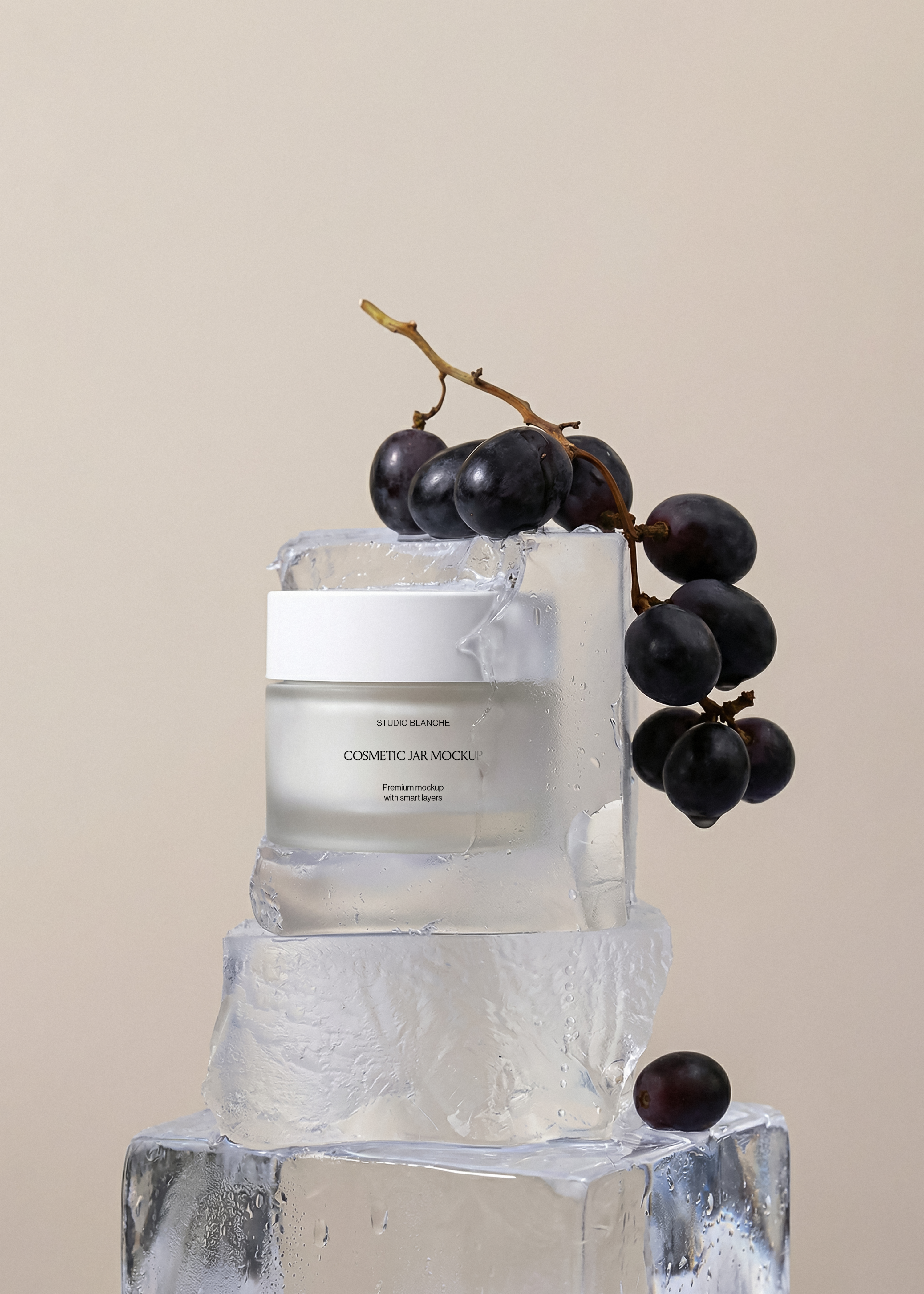 Frosted cosmetic jar mockup on wet ice cubes with bunch of black grapes draped over, fresh editorial scene