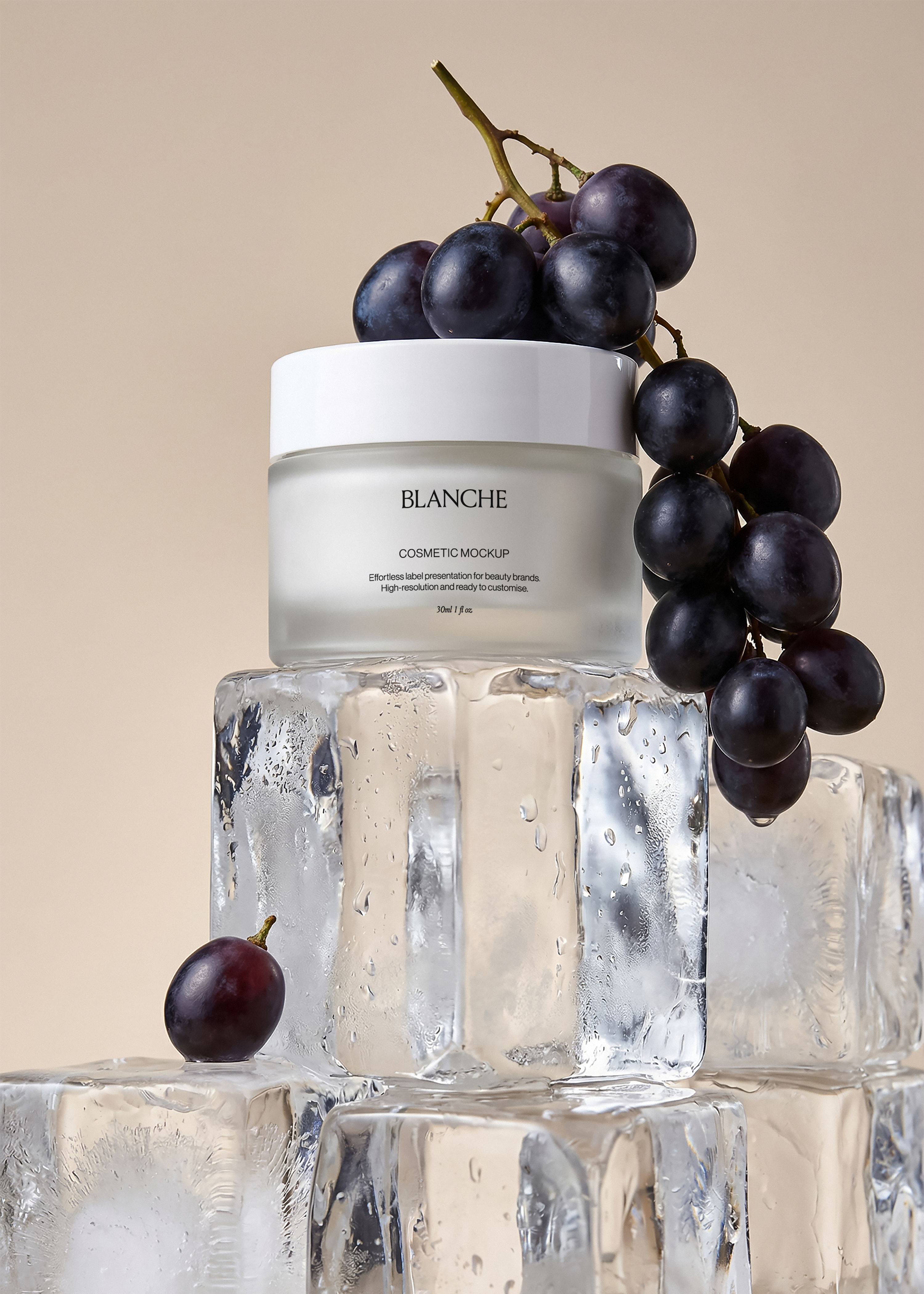 Frosted cosmetic jar mockup with white lid on large ice cube with dark grapes draped, warm beige backdrop