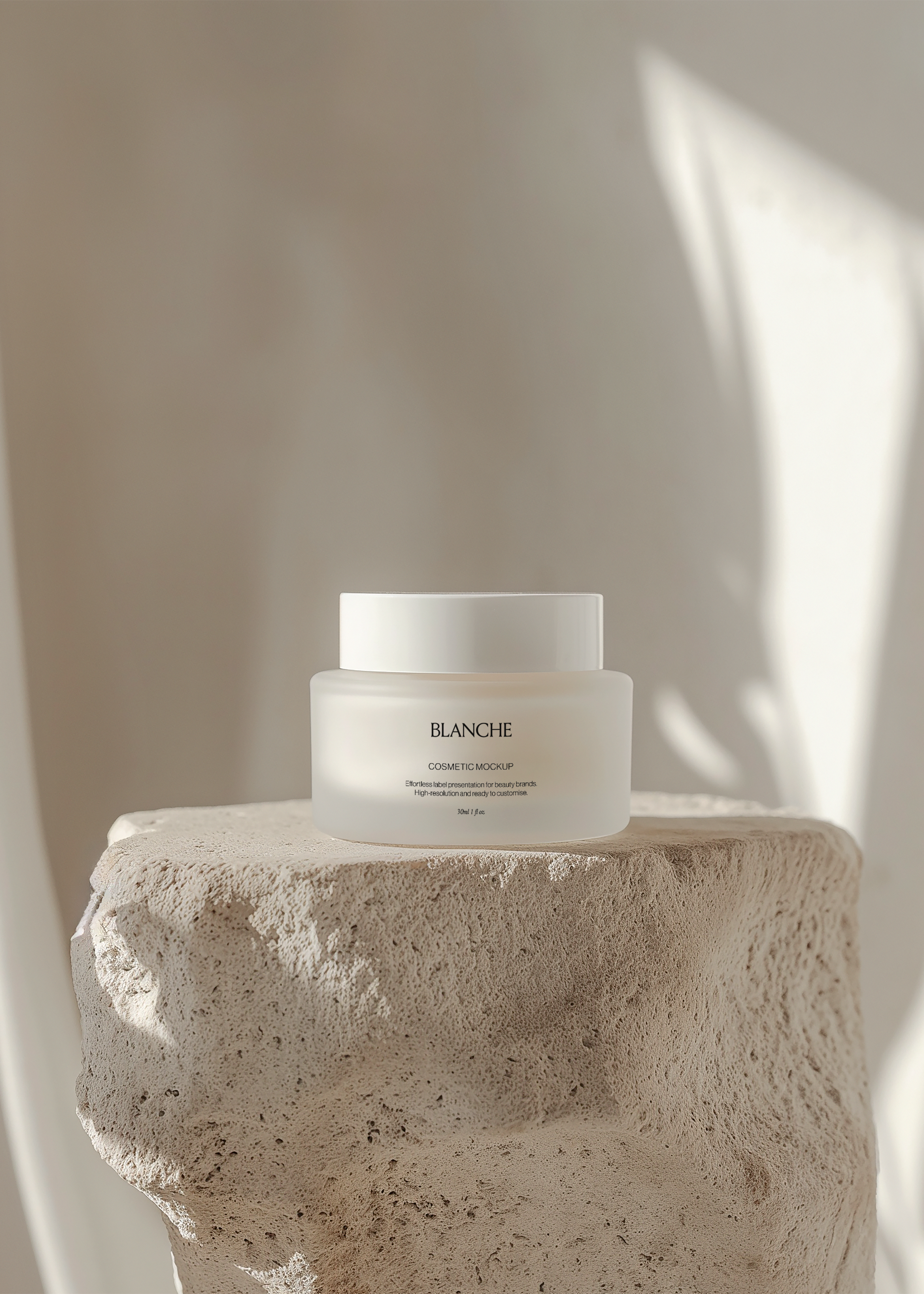 Frosted glass cosmetic jar mockup with matching lid on rough stone plinth, sunlit plaster wall and leaf shadow