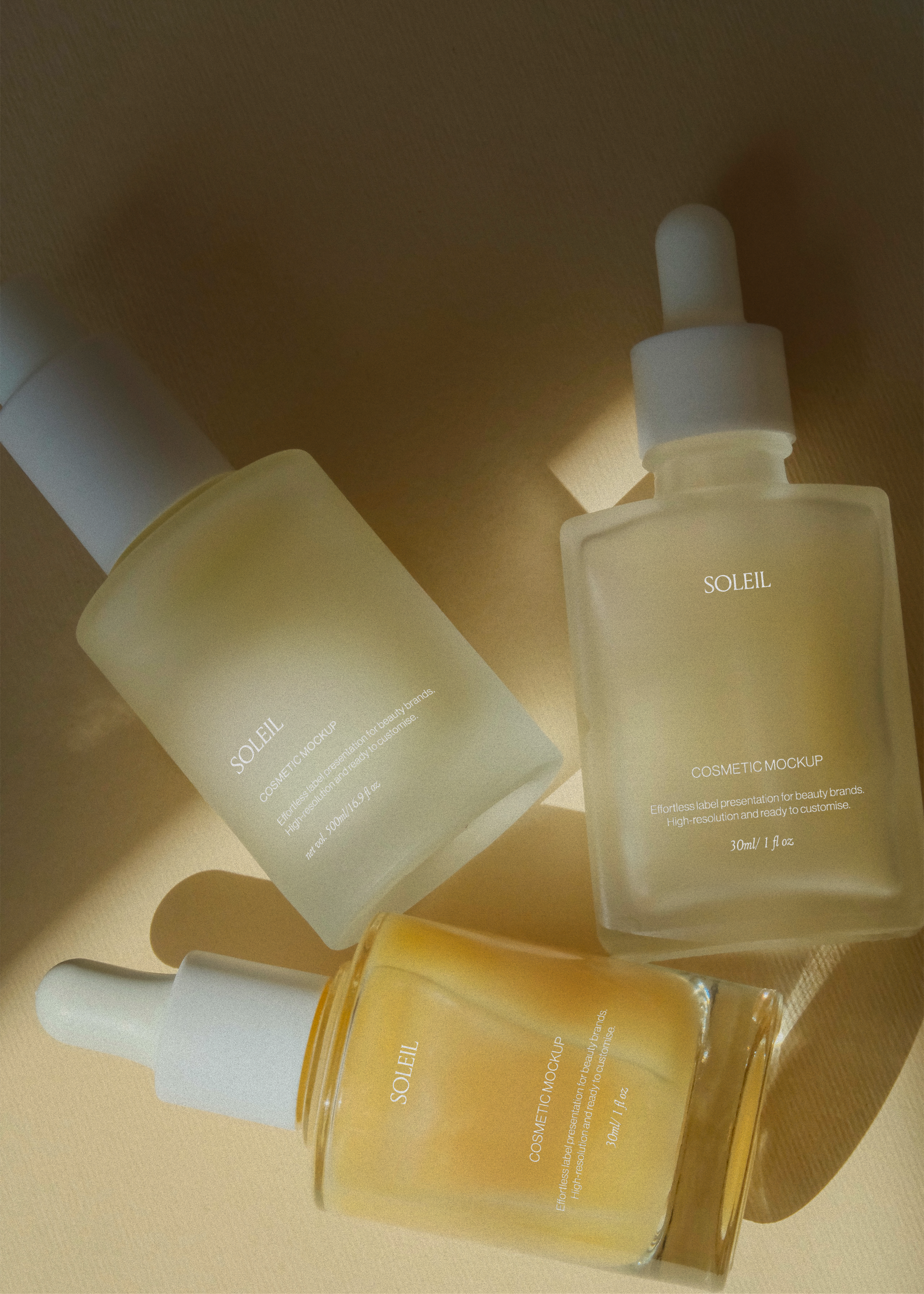 Pump bottle and two dropper bottles scattered across warm beige surface, hard directional light and long cast shadows
