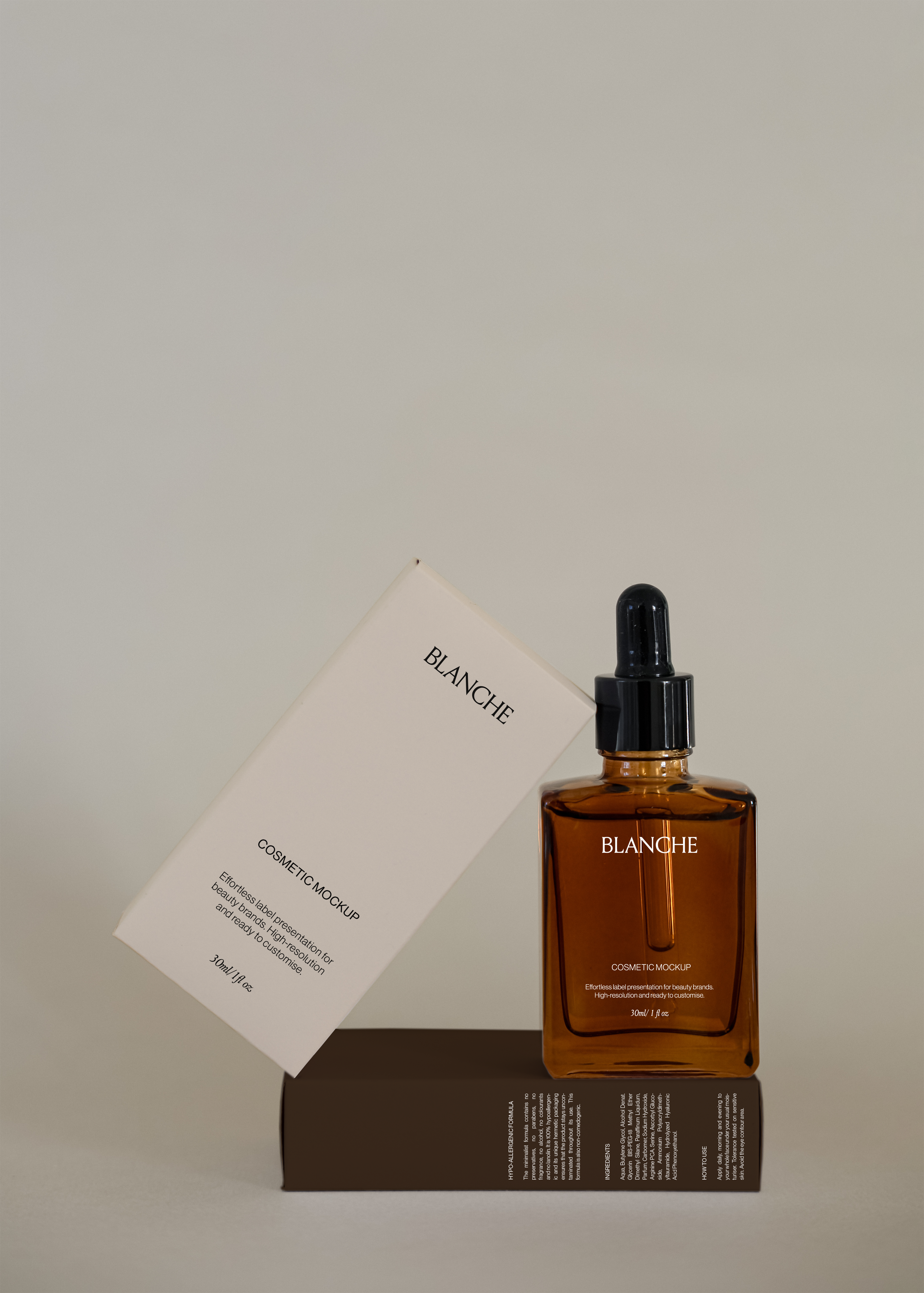 Amber glass dropper bottle mockup upright beside leaning cream box on dark base against neutral studio backdrop