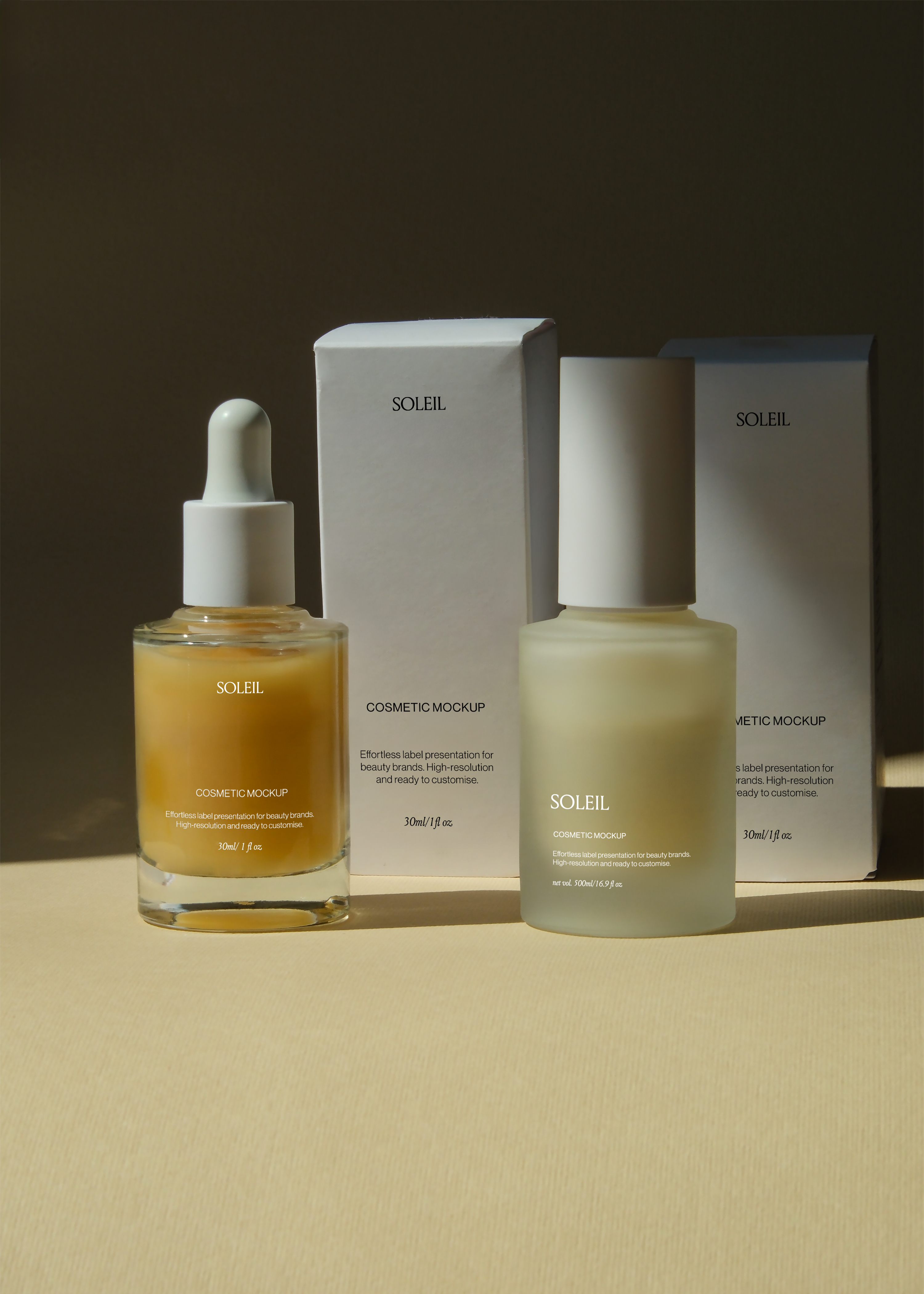 Amber dropper bottle, frosted pump bottle, and two matching cosmetic boxes arranged together, warm afternoon light on tan surface