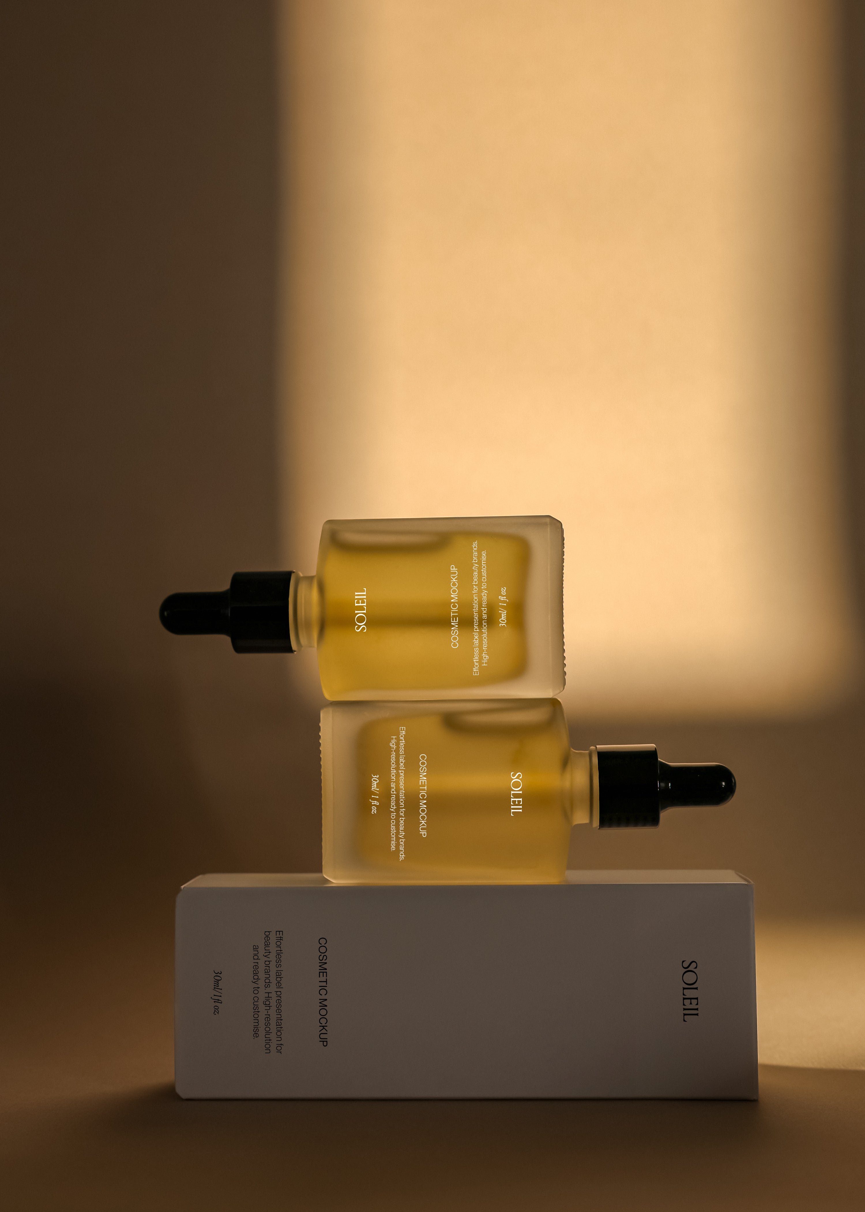 Two amber dropper bottles stacked directly on a cosmetic box, black pipette caps facing outward, warm backlit glow