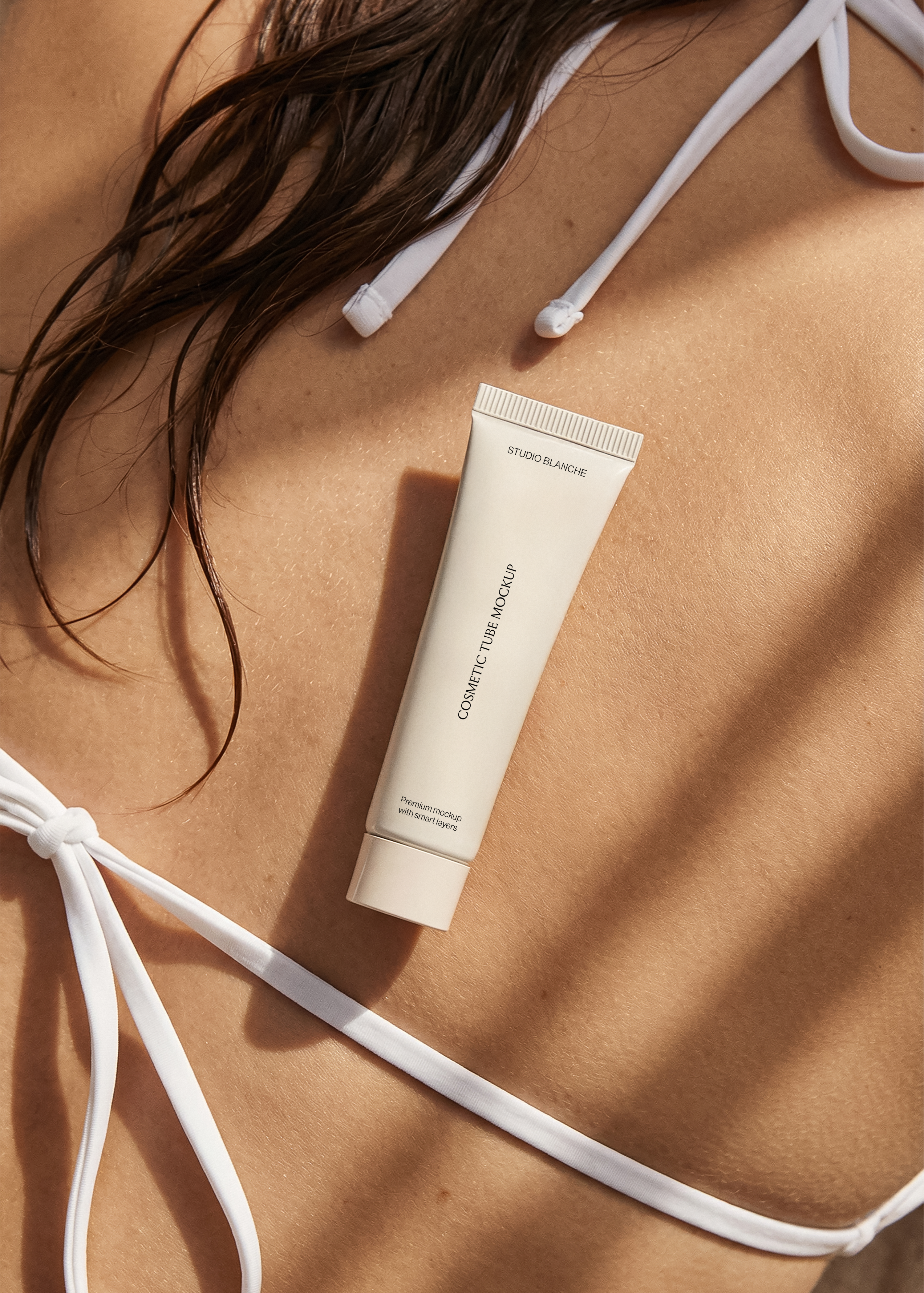 Flat cream cosmetic tube mockup on tanned skin with dappled shadow, warm beauty lifestyle scene
